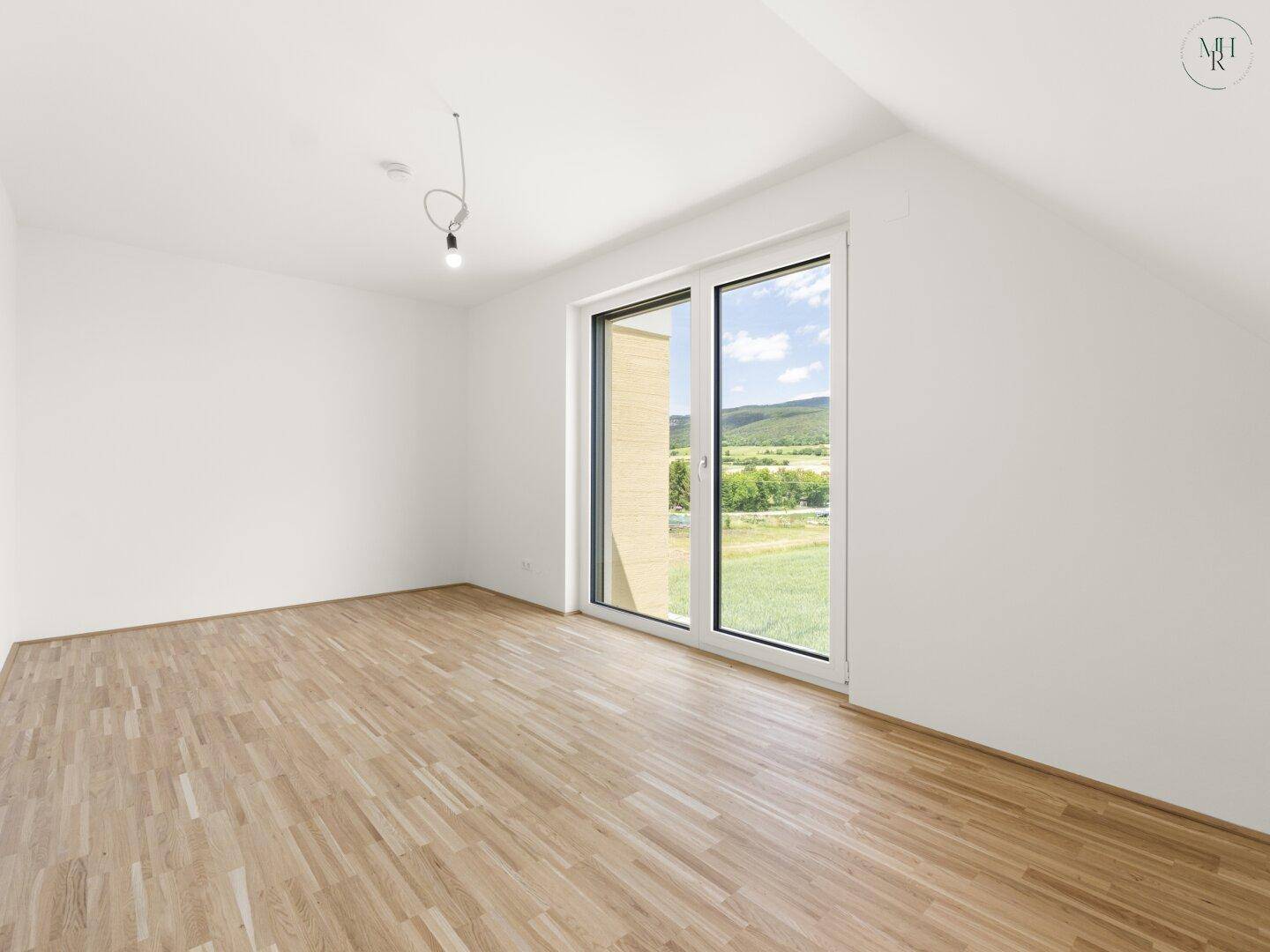Helles Schlafzimmer im Dachgeschoss mit Holzboden und weitem Blick in die Landschaft.