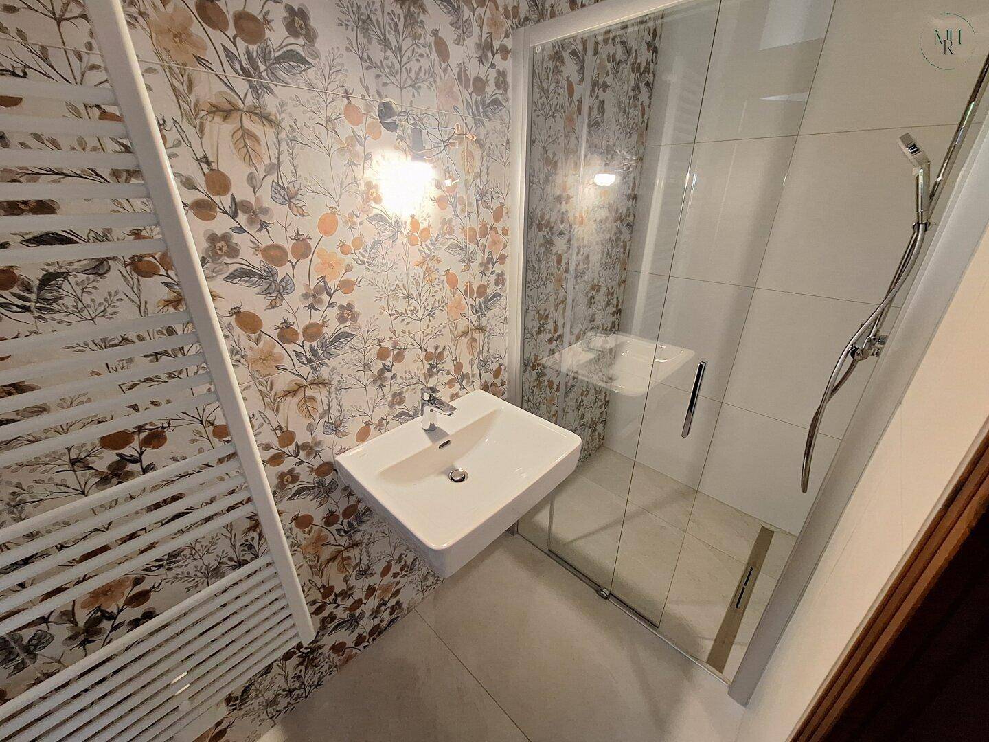 Modernes Badezimmer mit floraler Tapete, Duschkabine und beheiztem Handtuchhalter.