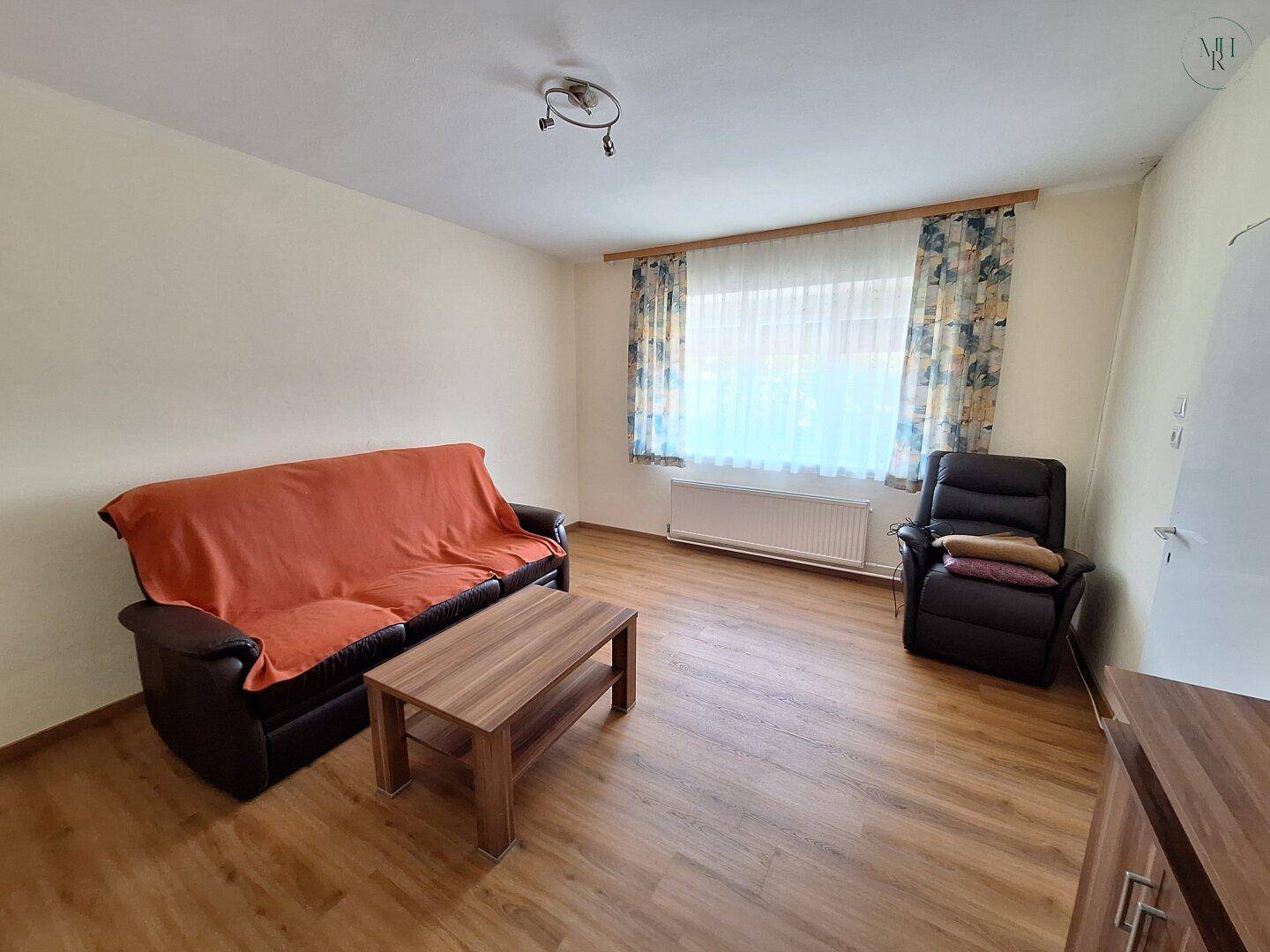 Helles Wohnzimmer mit Laminatboden, einem Sofa und einem Couchtisch, ideal für entspannte Stunden.