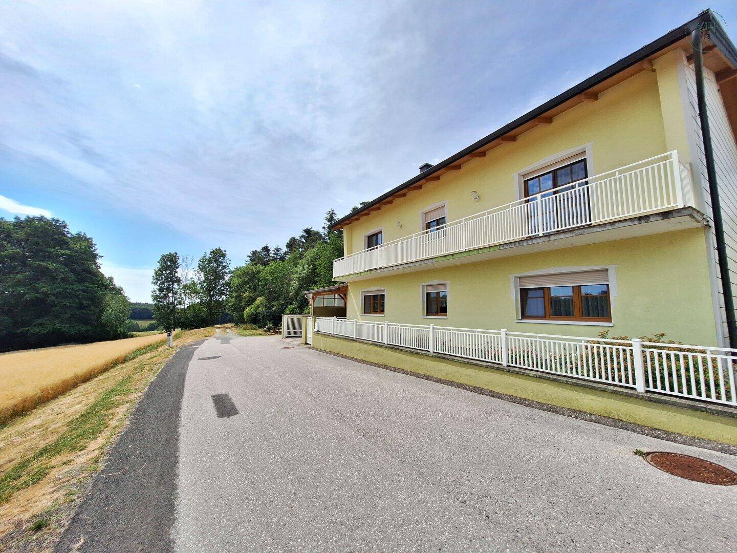 Ansicht des Hauses von der Zufahrt aus, umgeben von Feldern und Wäldern, in ländlicher Lage.