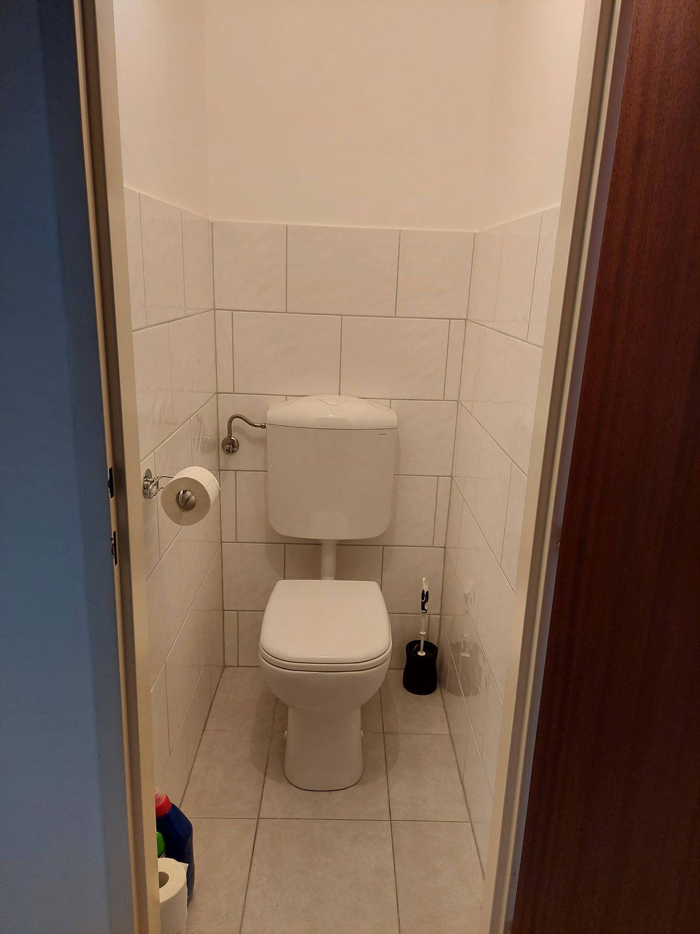 Kleines separates WC mit weißen Fliesen und Standard-Toilette.