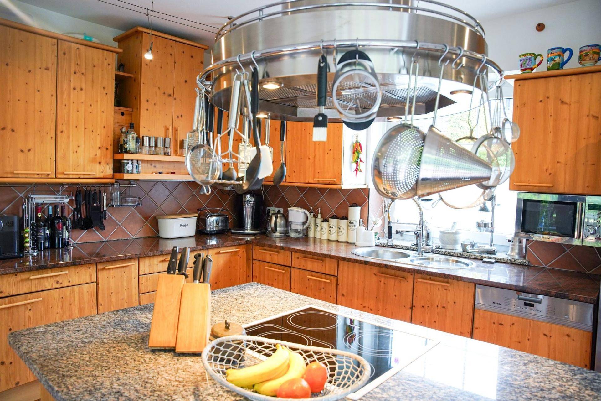 Detailansicht der Holzküche mit Kücheninsel, Granitarbeitsplatte und modernen Kochfeldern.