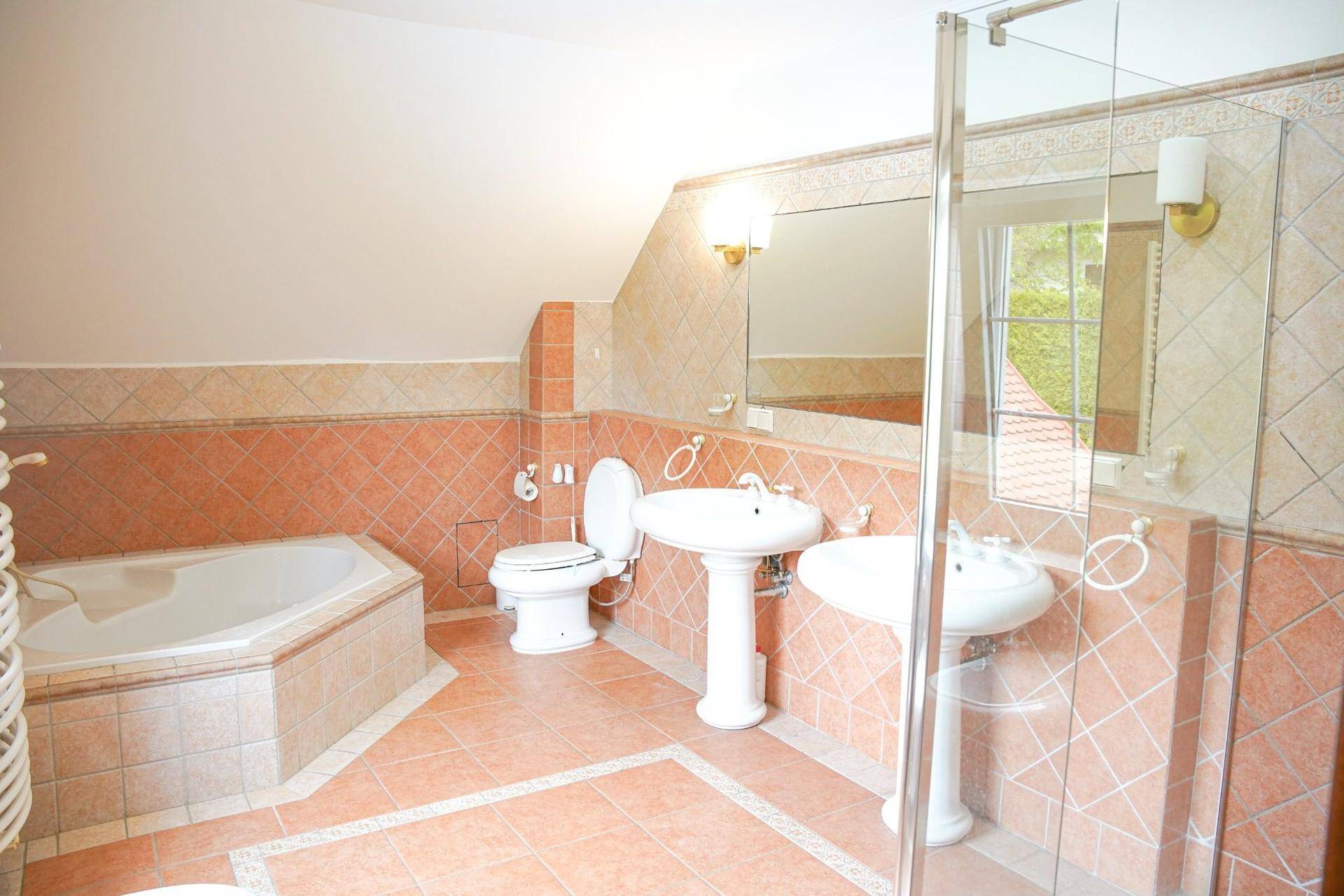 Geräumiges Badezimmer mit Eckbadewanne, Dusche, WC und zwei Waschbecken.
