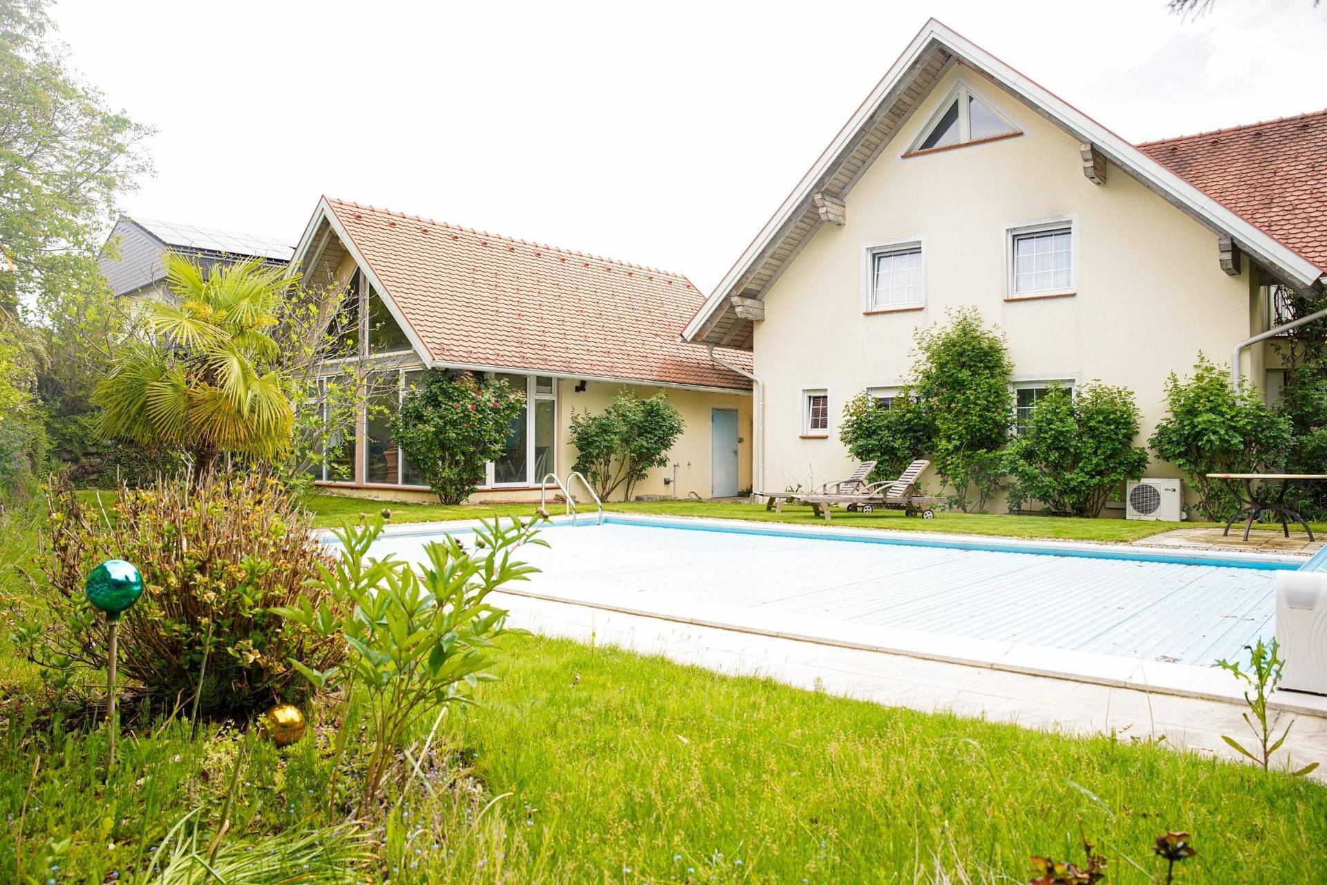 Weitläufiger Gartenbereich mit einem Swimmingpool und zwei Wohnhäusern im Hintergrund.