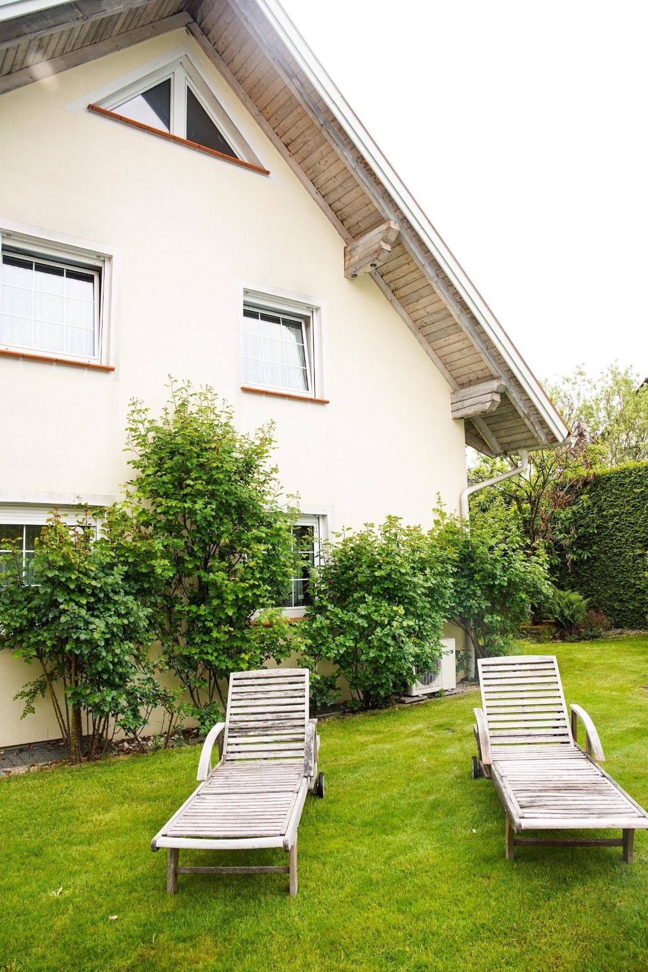 Großer Rasenbereich am Haus mit zwei Sonnenliegen, ideal zum Entspannen im Freien.