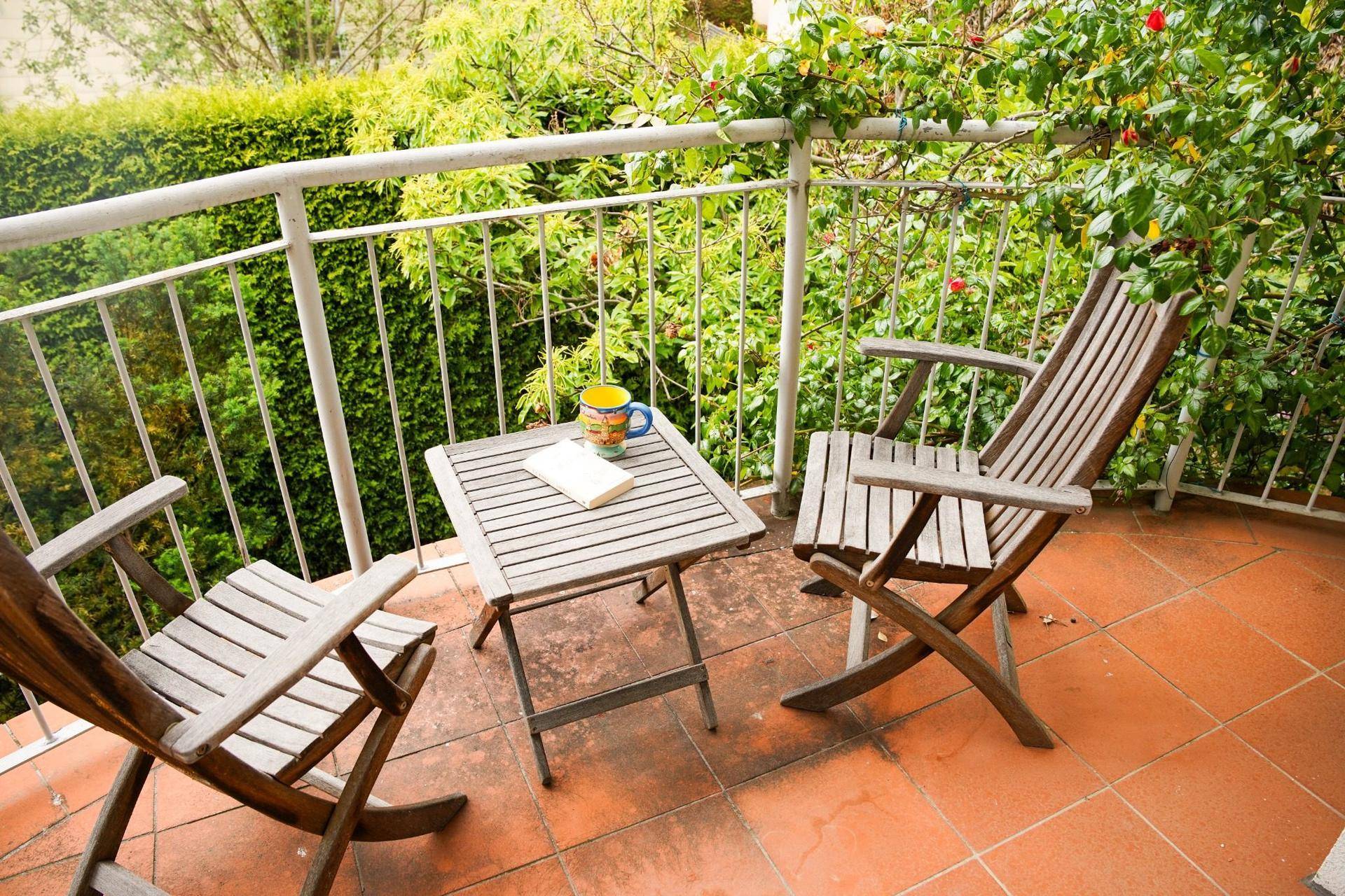 Kleiner Balkon mit Holzsitzgruppe, ideal für eine Tasse Kaffee im Grünen.