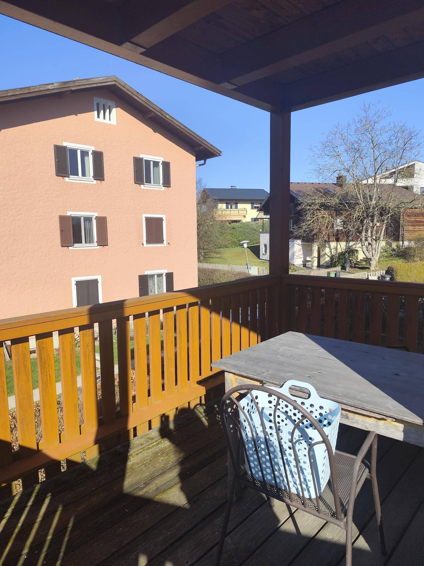 Geräumiger Balkon mit Holzboden und Sitzgelegenheiten, bietet einen Blick auf die Nachbarschaft.