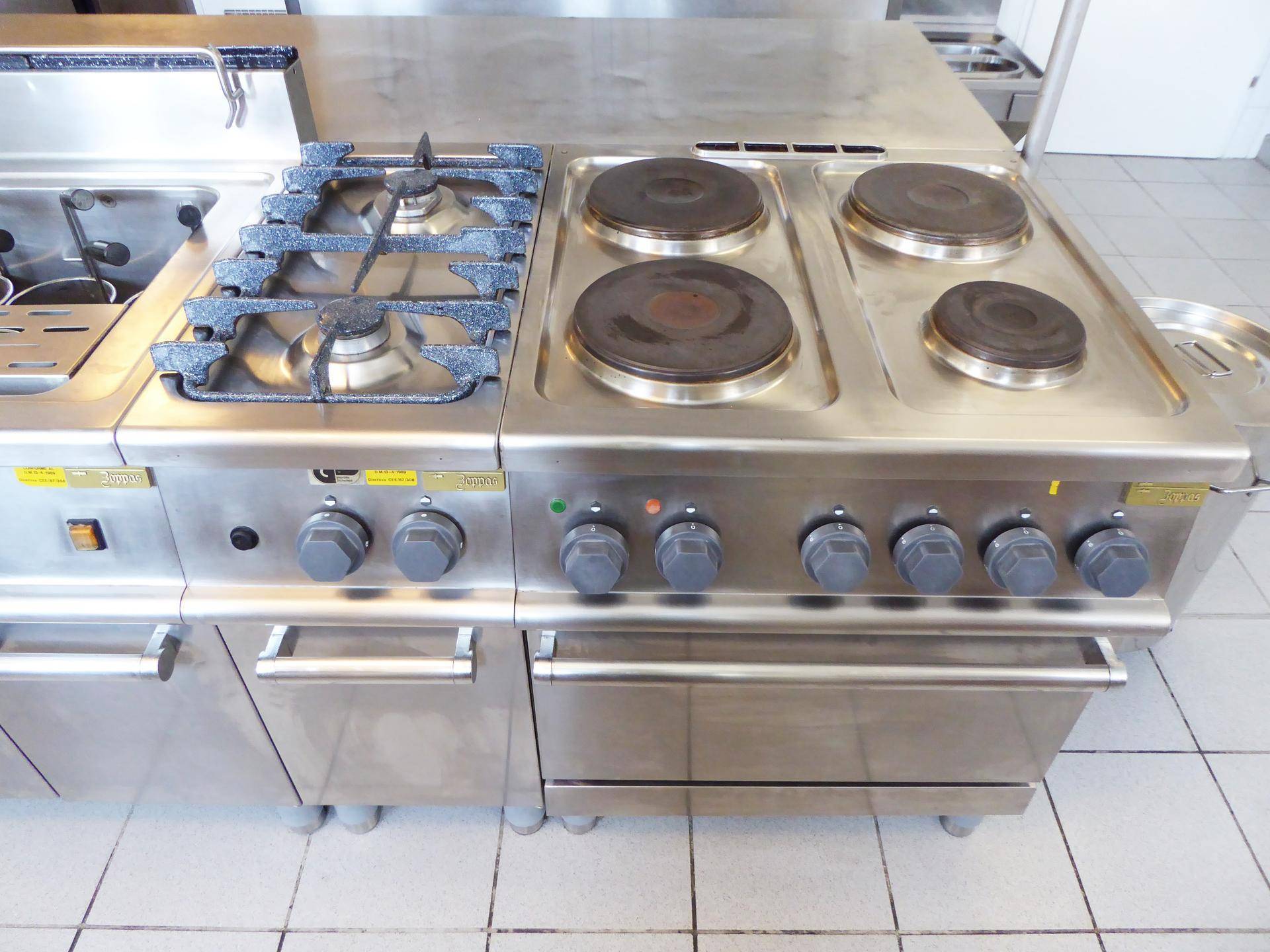 Große Kochinsel mit Gasherd, Elektrokochplatten und einem Backofen aus Edelstahl.