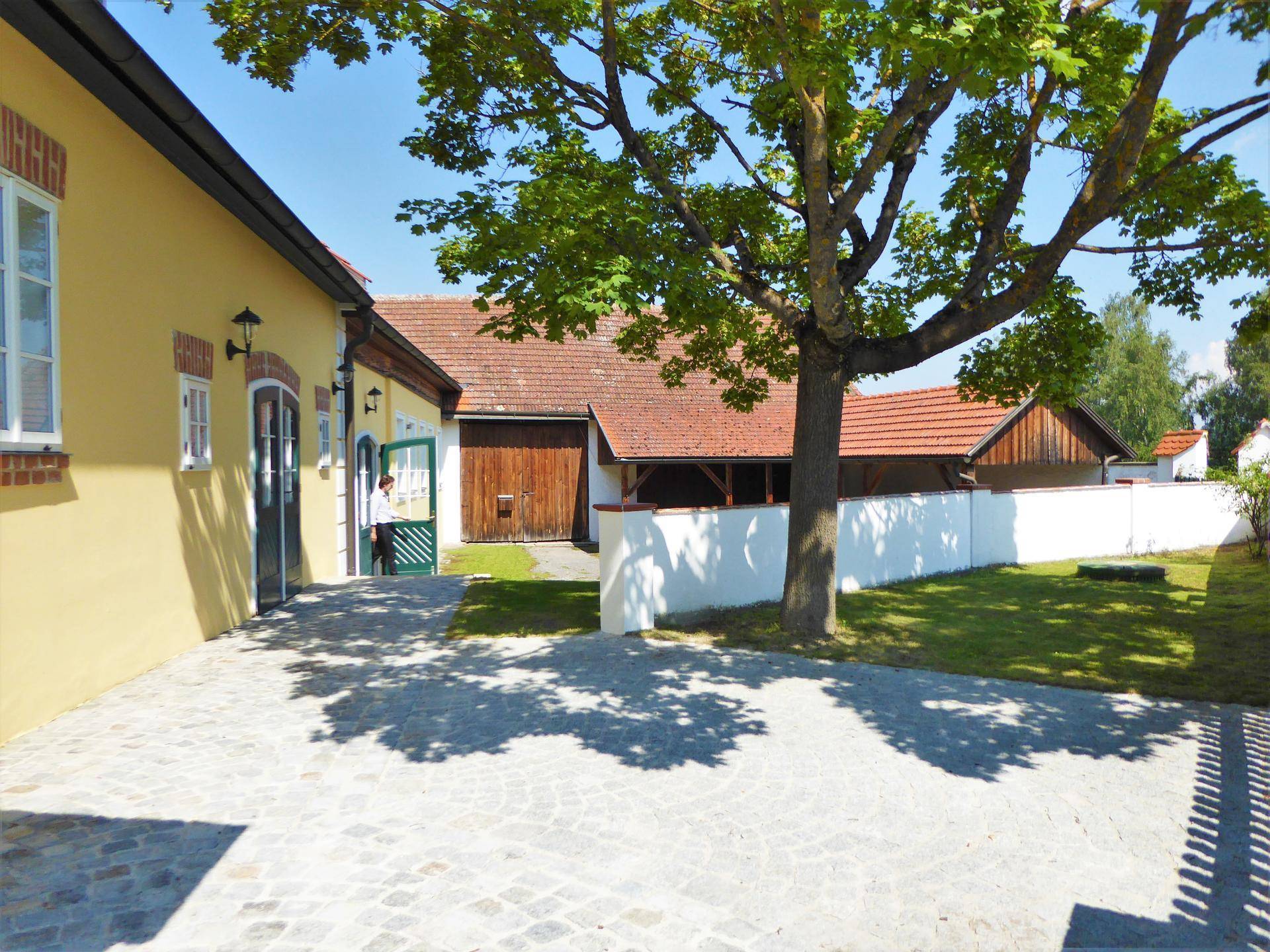 Gepflasterter Innenhof mit einem Baum und Blick auf weitere traditionelle Gebäude im Hintergrund.