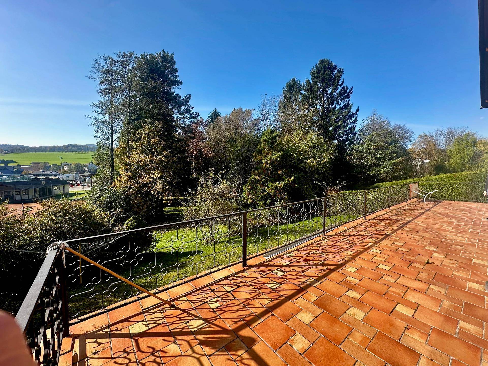 Große geflieste Terrasse mit schmiedeeisernem Geländer und weitem Blick über die Landschaft.
