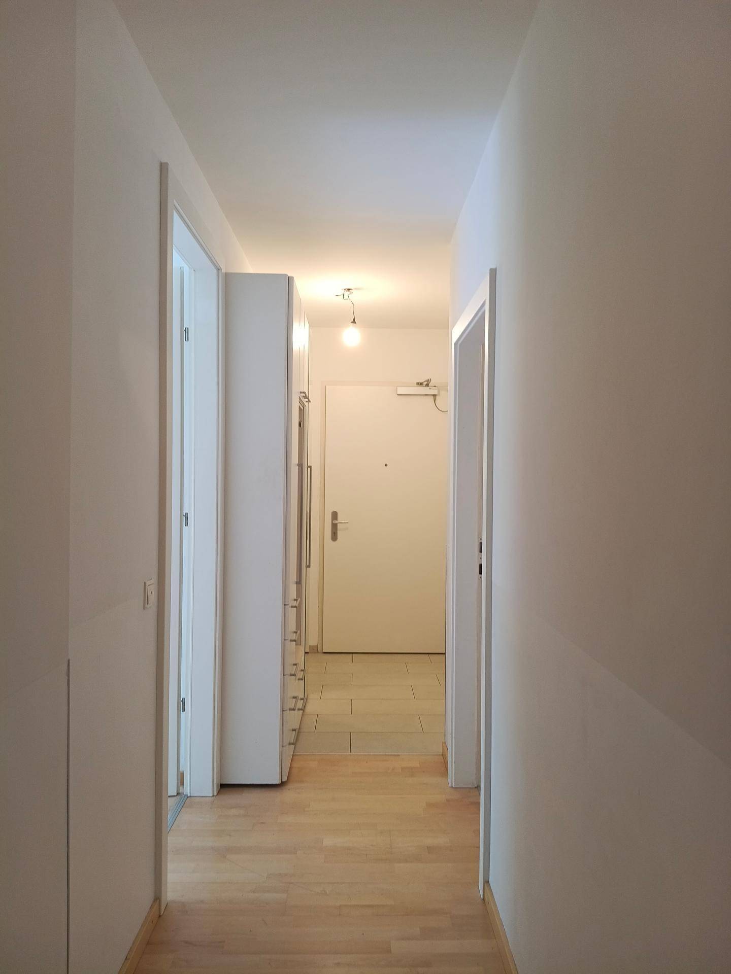 Eingangsbereich mit Holzboden und Fliesen, der zu einer Garderobe und weiteren Räumen führt.