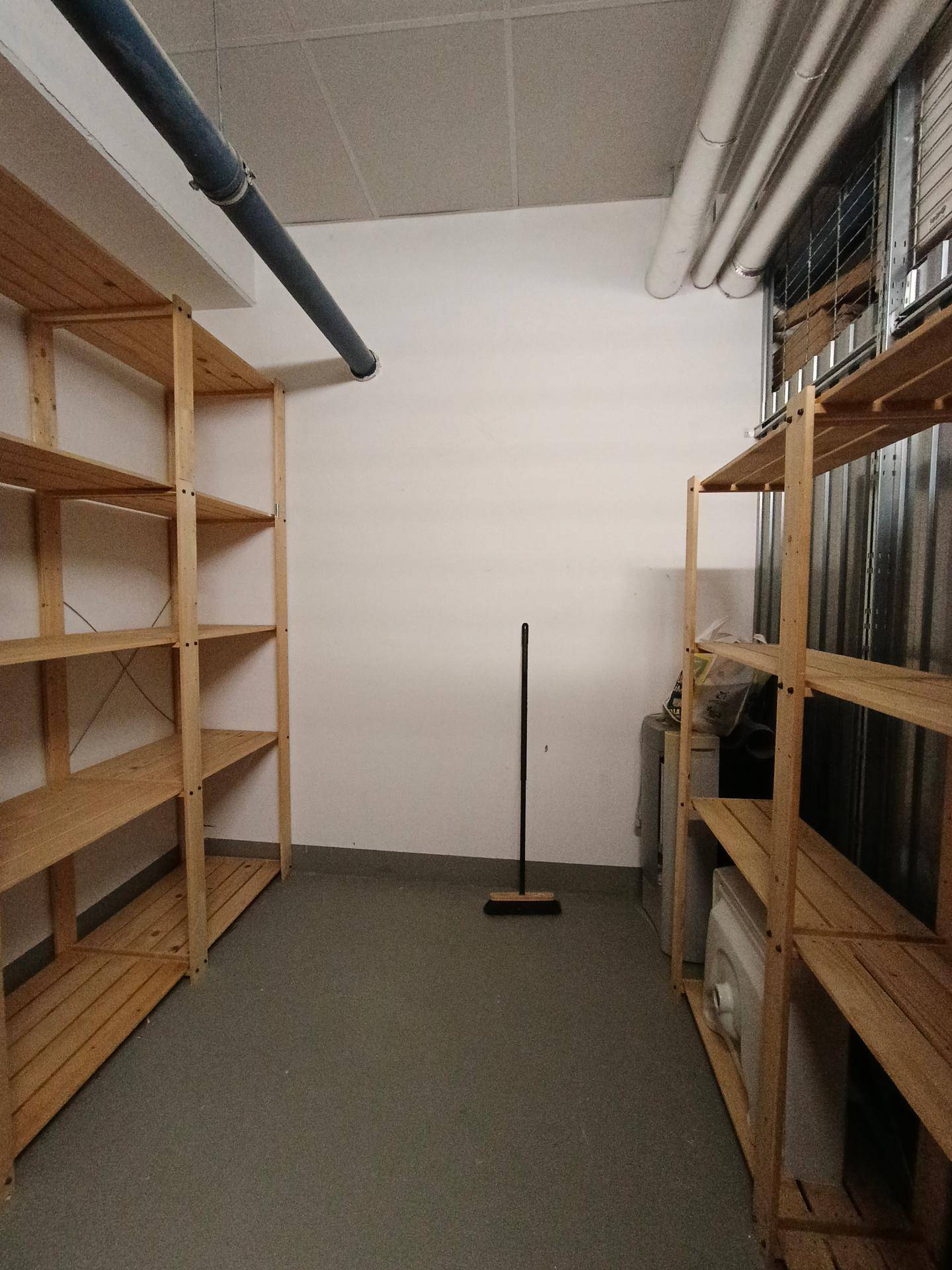 Geräumiger Abstellraum mit Holzregalen und Betonboden, ideal für zusätzliche Lagerung.