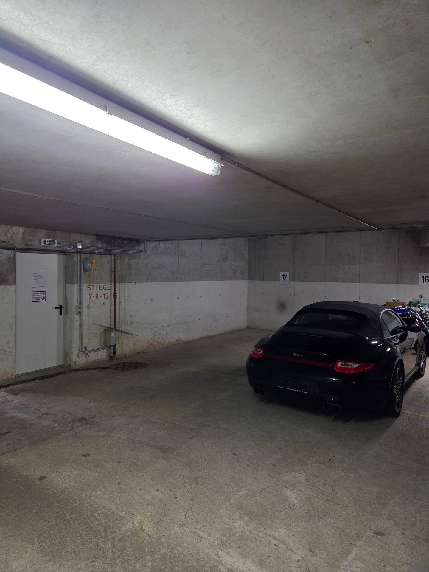 Tiefgaragenstellplatz mit einem geparkten Sportwagen und Zugang zu einem Treppenhaus.