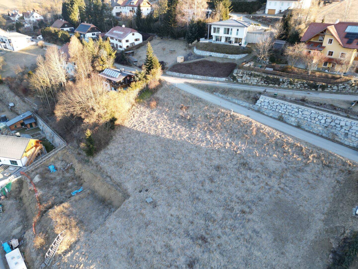 Weitläufige Luftaufnahme eines unbebauten Grundstücks mit umliegenden Wohnhäusern und Straßen.