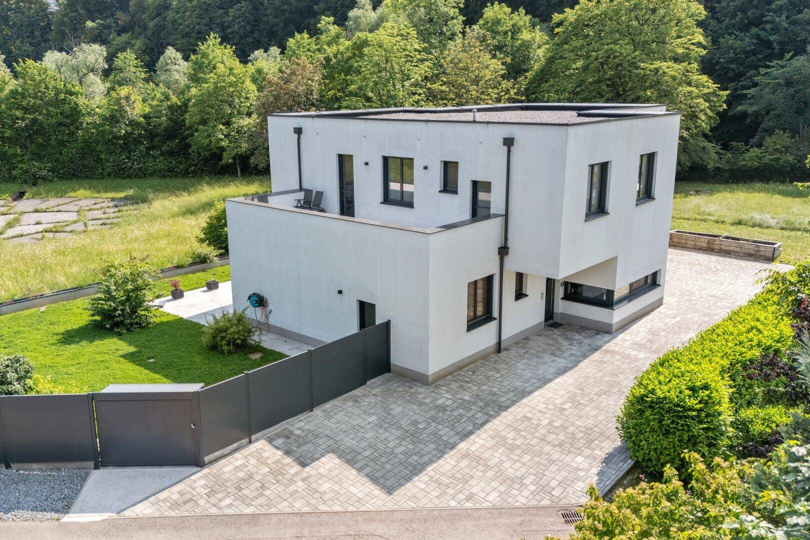 Ansicht des modernen Hauses mit gepflasterter Auffahrt und minimalistischer Fassadengestaltung.