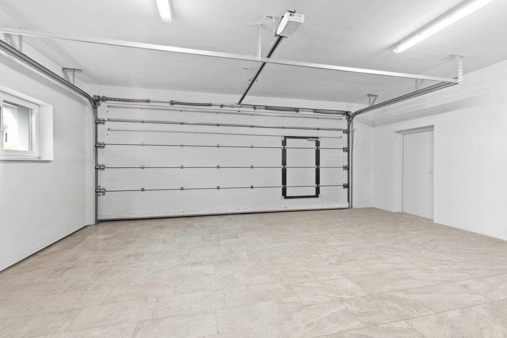 Geräumige Garage mit automatischem Tor, Fenster und Fliesenboden.