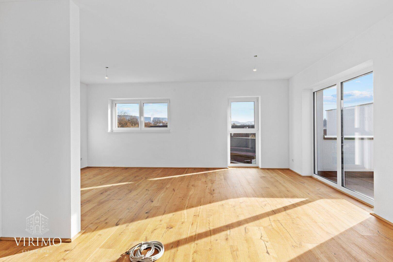 Heller, leerer Raum mit Holzboden und Zugang zu einem Balkon, ideal für Wohnbereich.