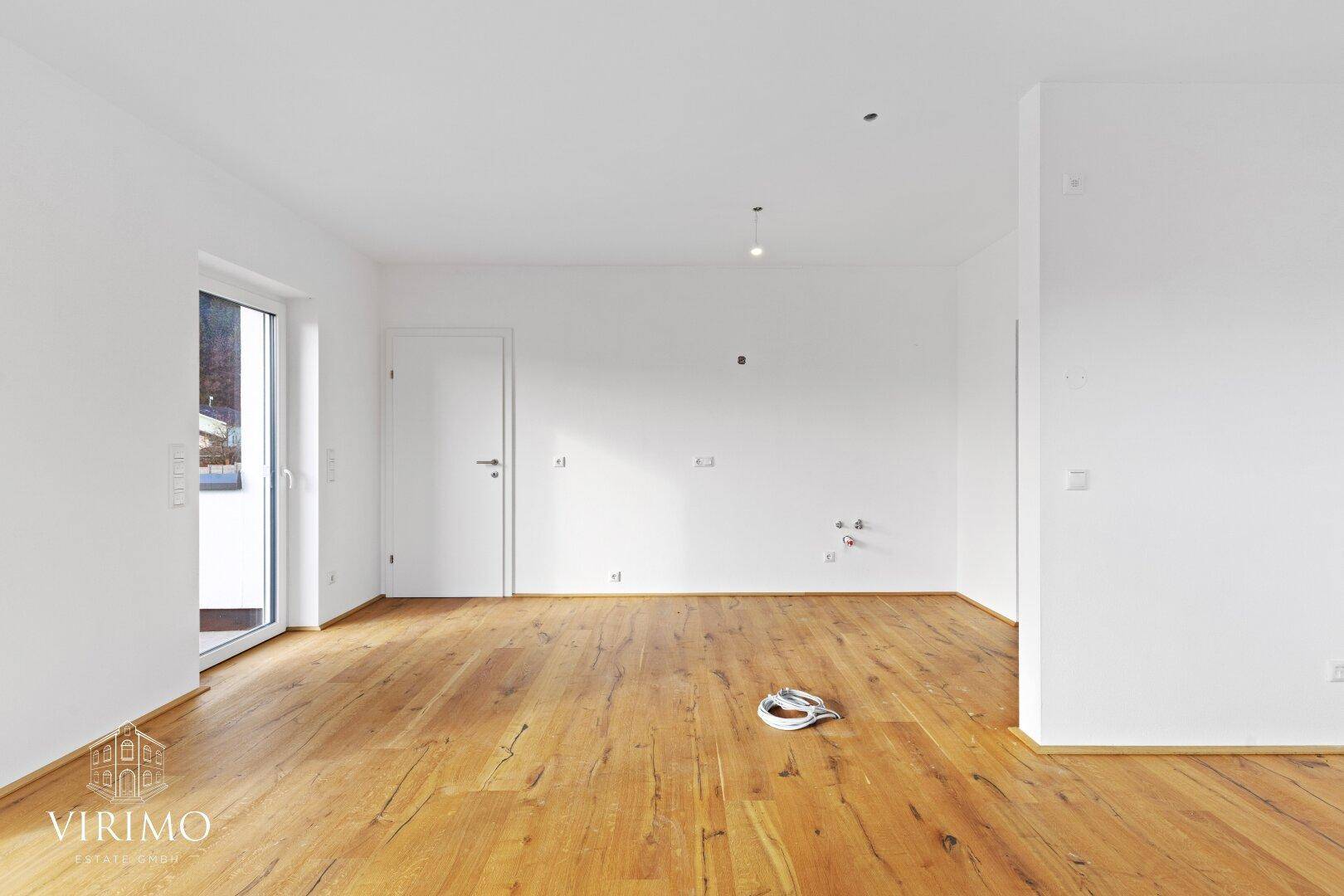 Geräumiger, heller Raum mit Holzboden und vorbereiteten Anschlüssen für eine zukünftige Nutzung.