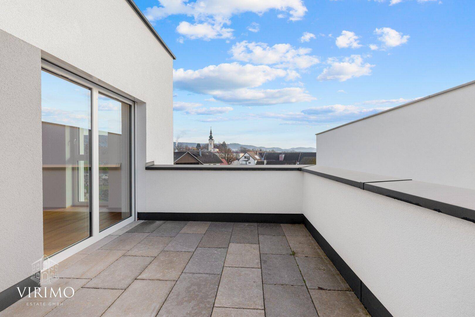Heller Balkon mit Fliesenboden und weitem Blick über die umliegende Landschaft.