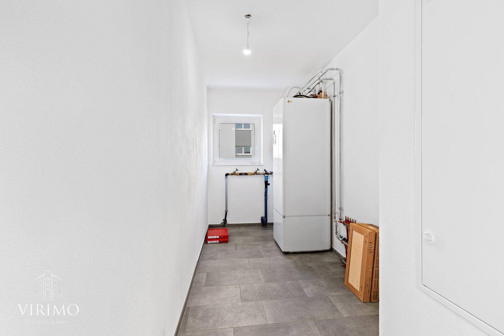 Funktionaler Hauswirtschaftsraum mit Heizungsanlage und Fenster für Belüftung.