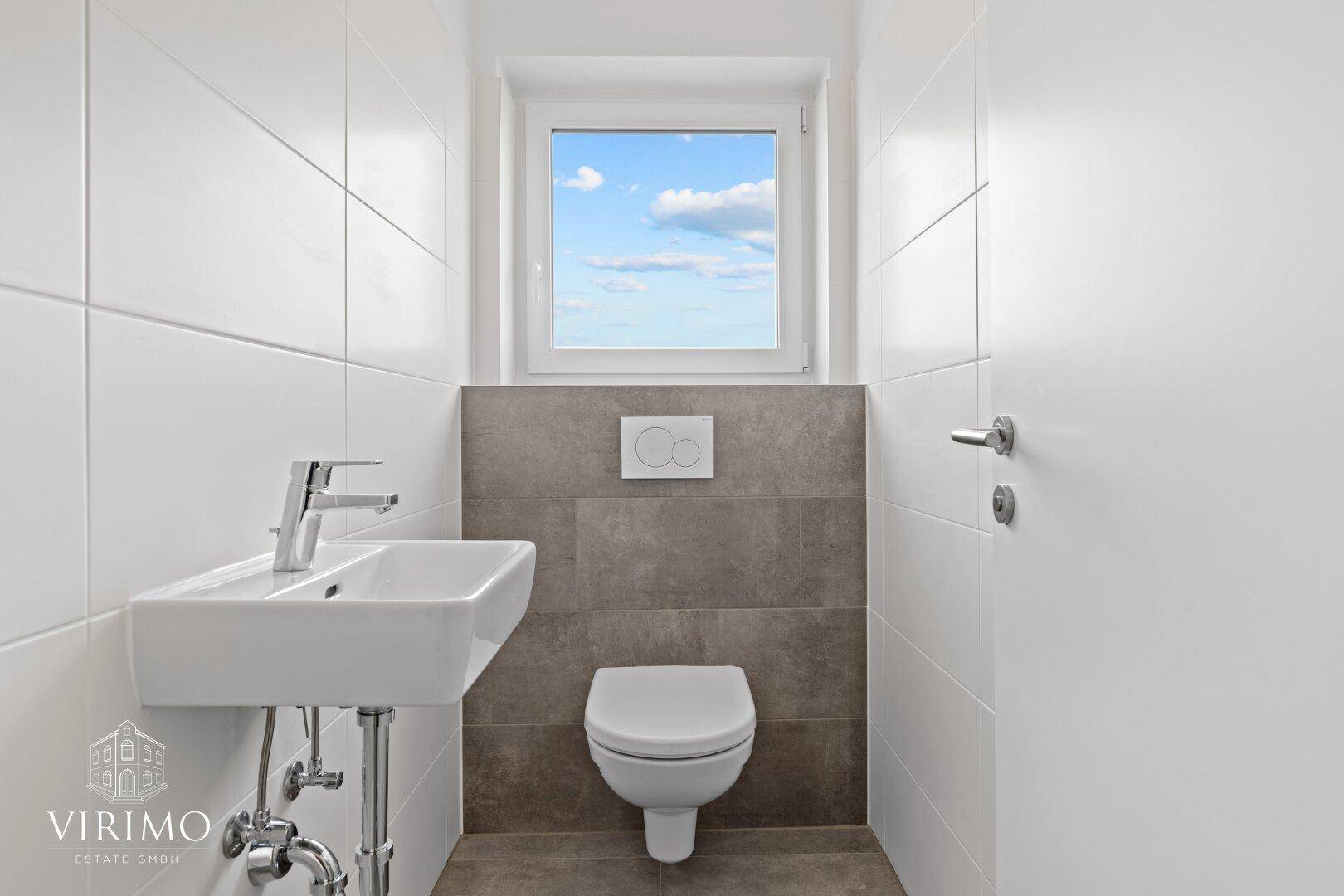 Modernes Gäste-WC mit Wand-WC, kleinem Waschbecken und Fenster für Tageslicht.