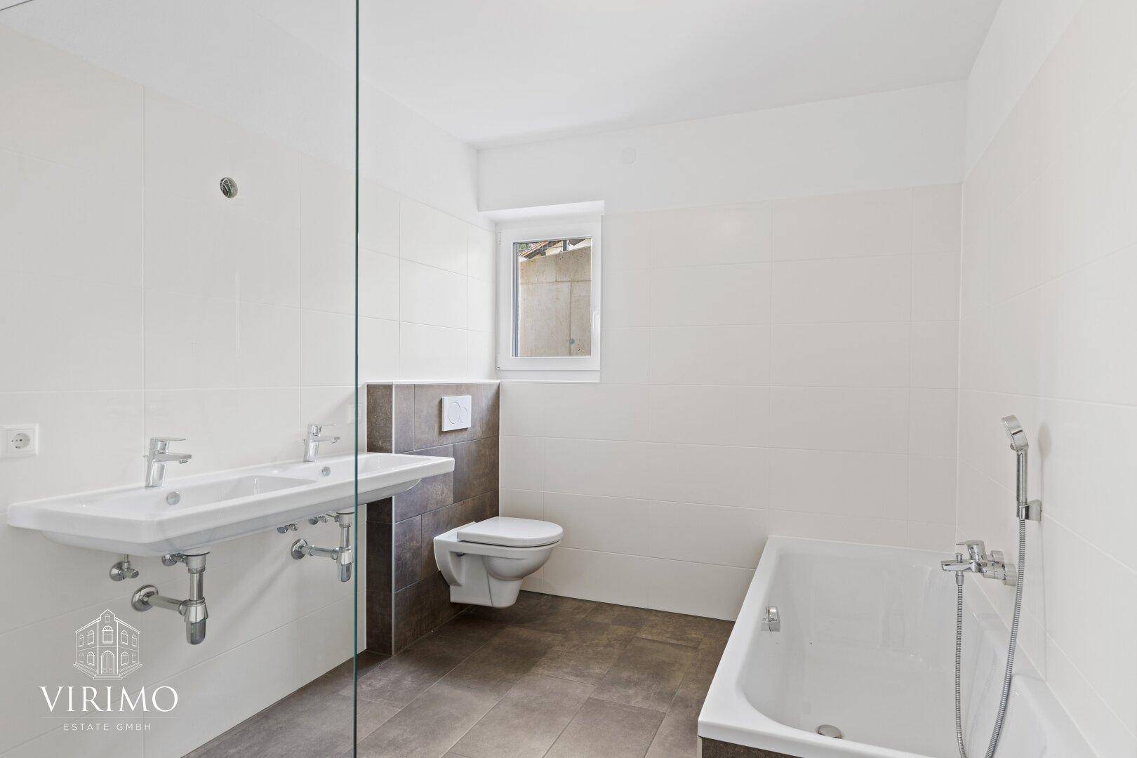 Modernes Badezimmer mit Badewanne, Waschbecken, Wand-WC und Fenster.