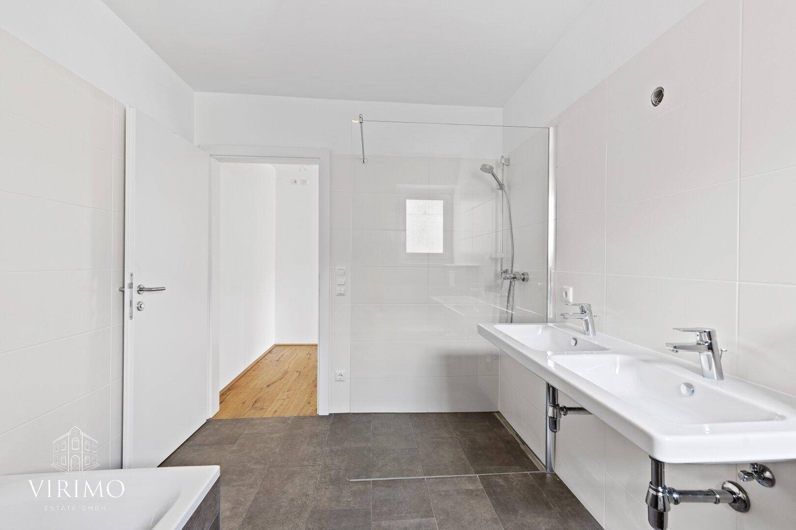 Geräumiges Badezimmer mit Doppelwaschbecken, großer Dusche und modernen Fliesen.