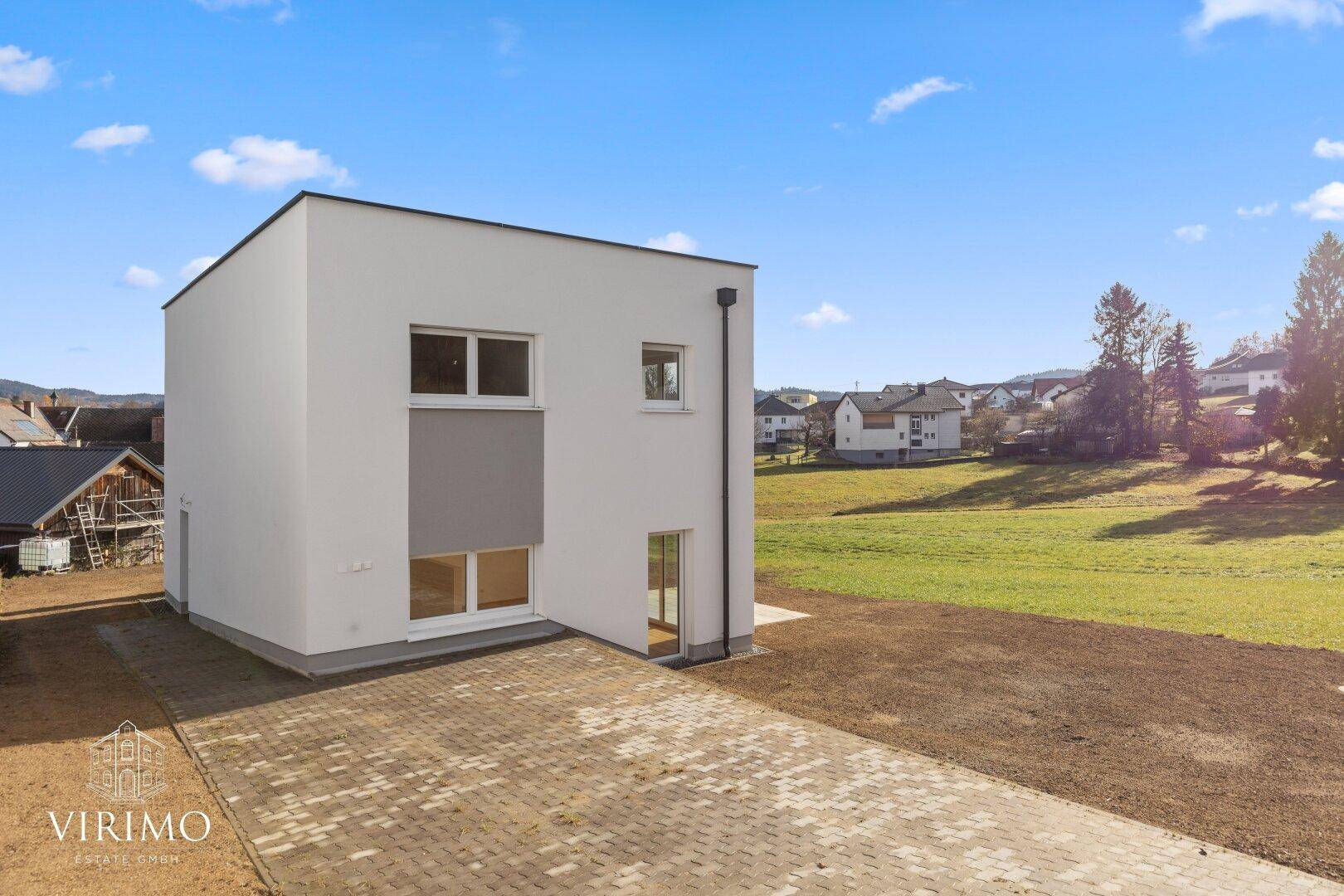 Moderne Neubau-Doppelhaushälfte mit gepflastertem Vorplatz und weitem Blick ins Grüne.
