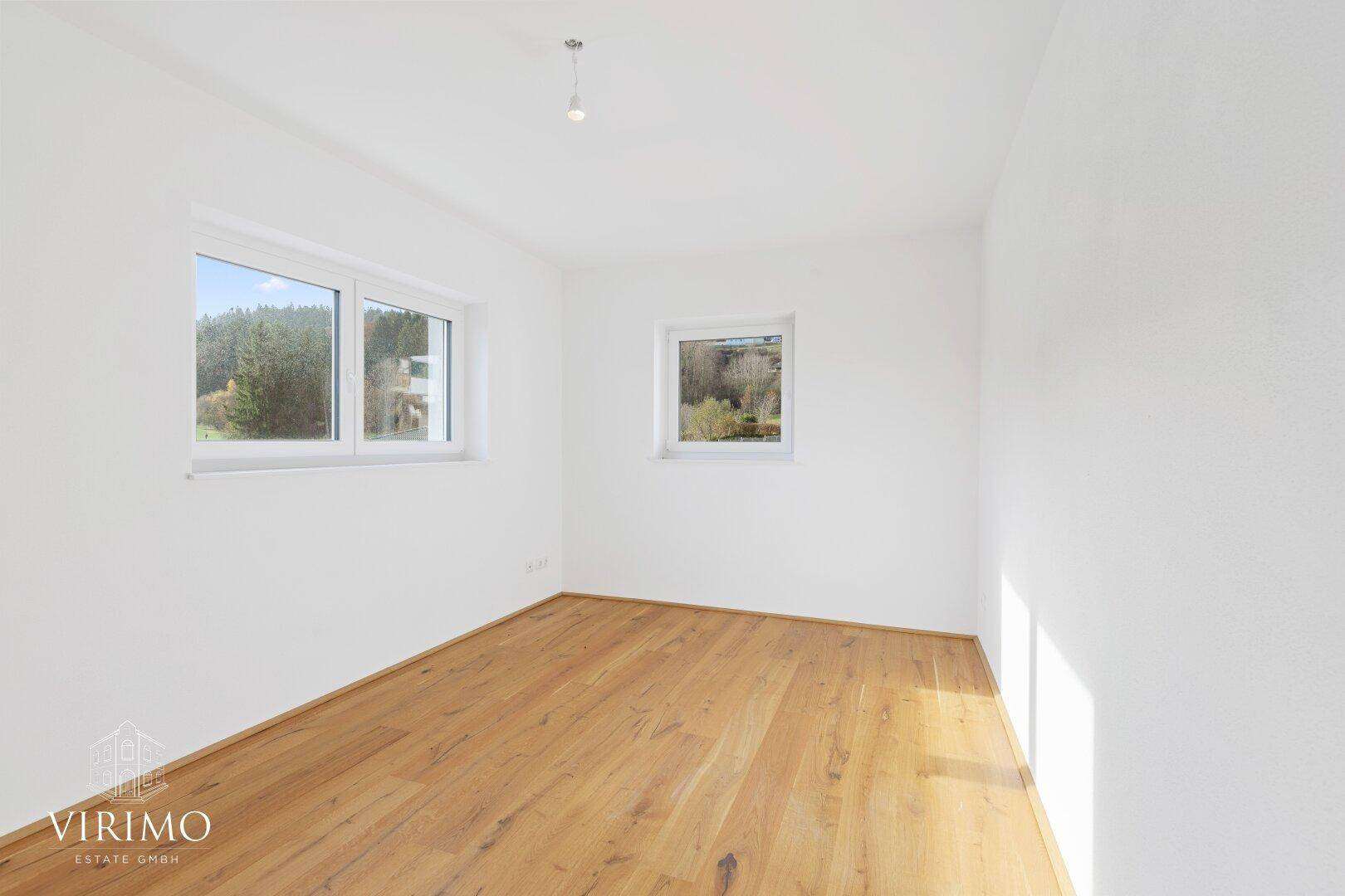 Geräumiges Schlafzimmer mit zwei Fenstern, Holzboden und viel natürlichem Lichteinfall.