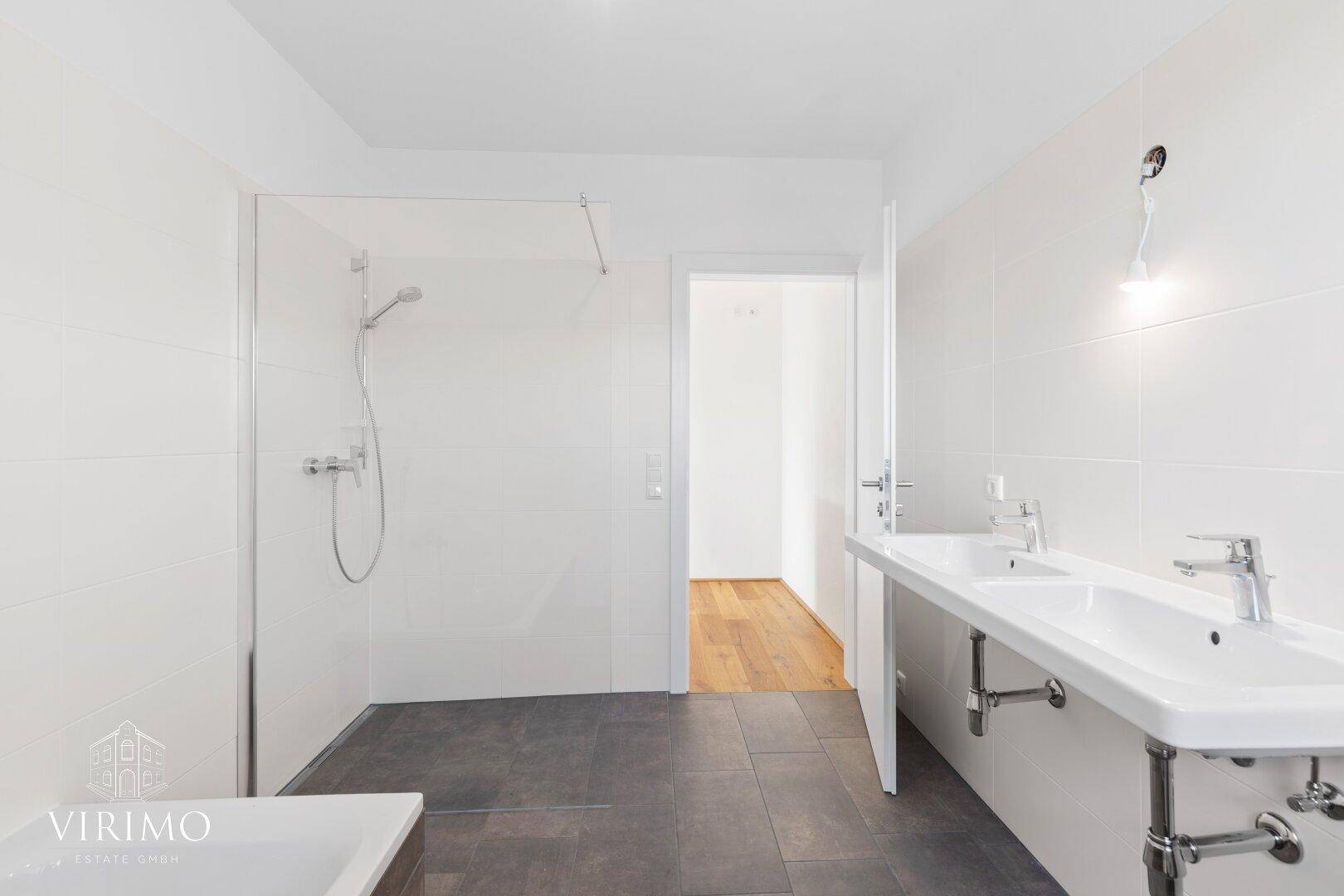 Modernes Badezimmer mit großer begehbarer Dusche und Doppelwaschbecken, hell und geräumig.