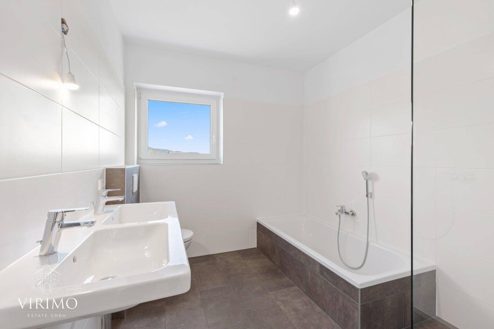 Modernes Badezimmer mit Doppelwaschbecken, Badewanne und Fenster für natürliche Belüftung.