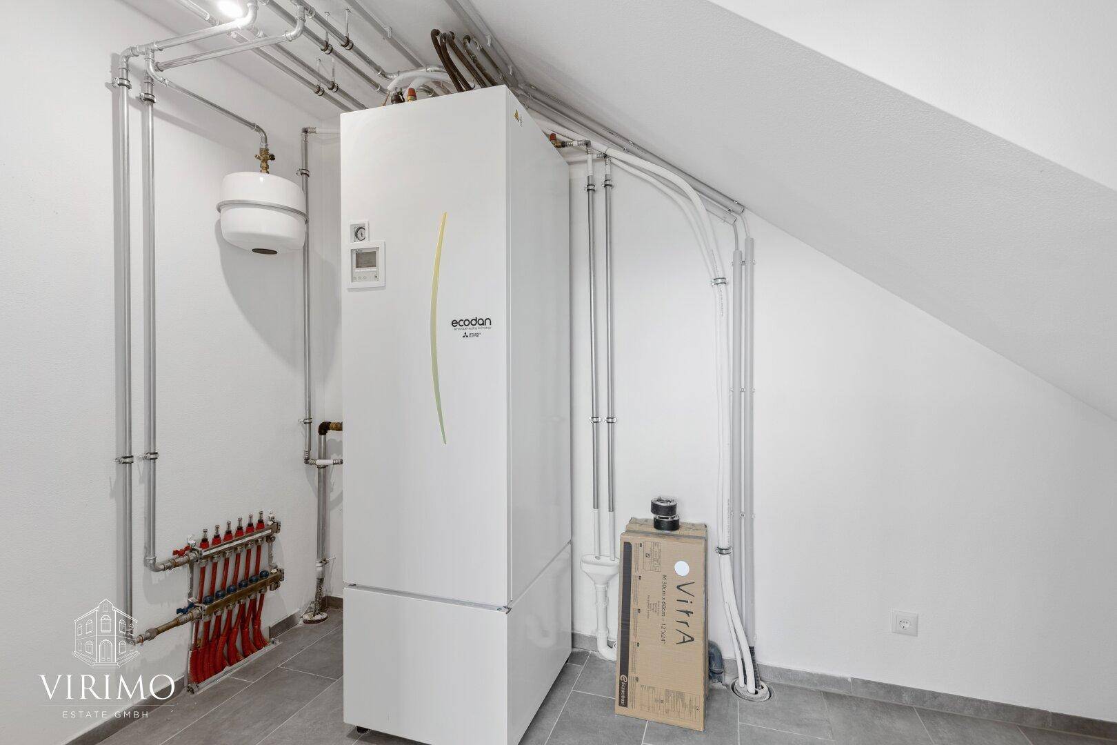 Technikraum mit moderner Wärmepumpe und Fußbodenheizungsverteiler unter dem Dach.