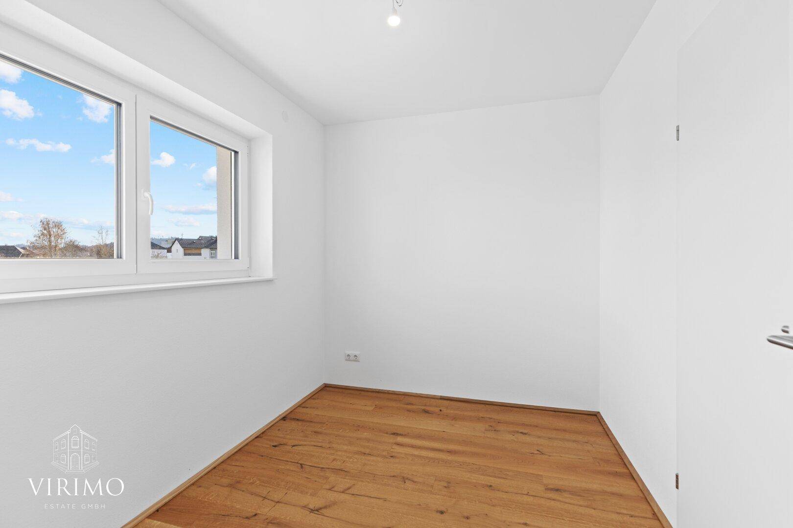 Kleiner, heller Raum mit Holzboden und einem Fenster, ideal als Kinder- oder Arbeitszimmer.