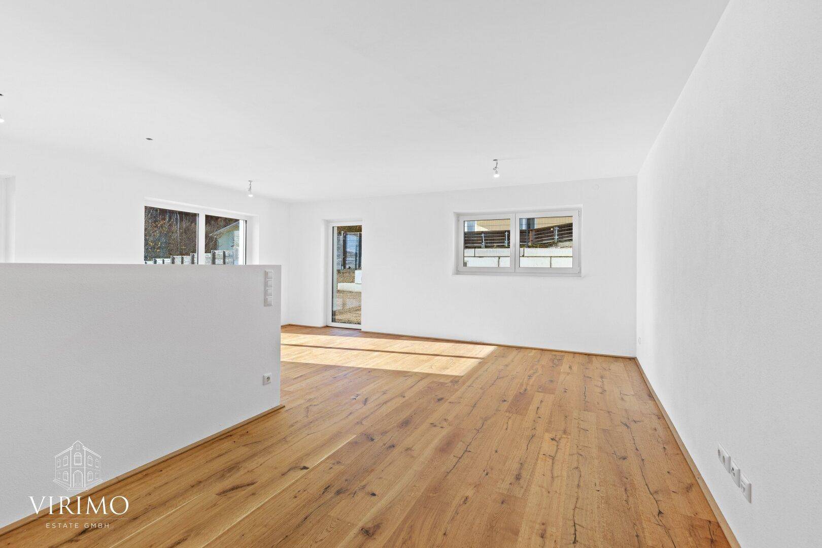 Heller, leerer Raum mit Holzboden und weißen Wänden, ideal für einen offenen Wohnbereich.