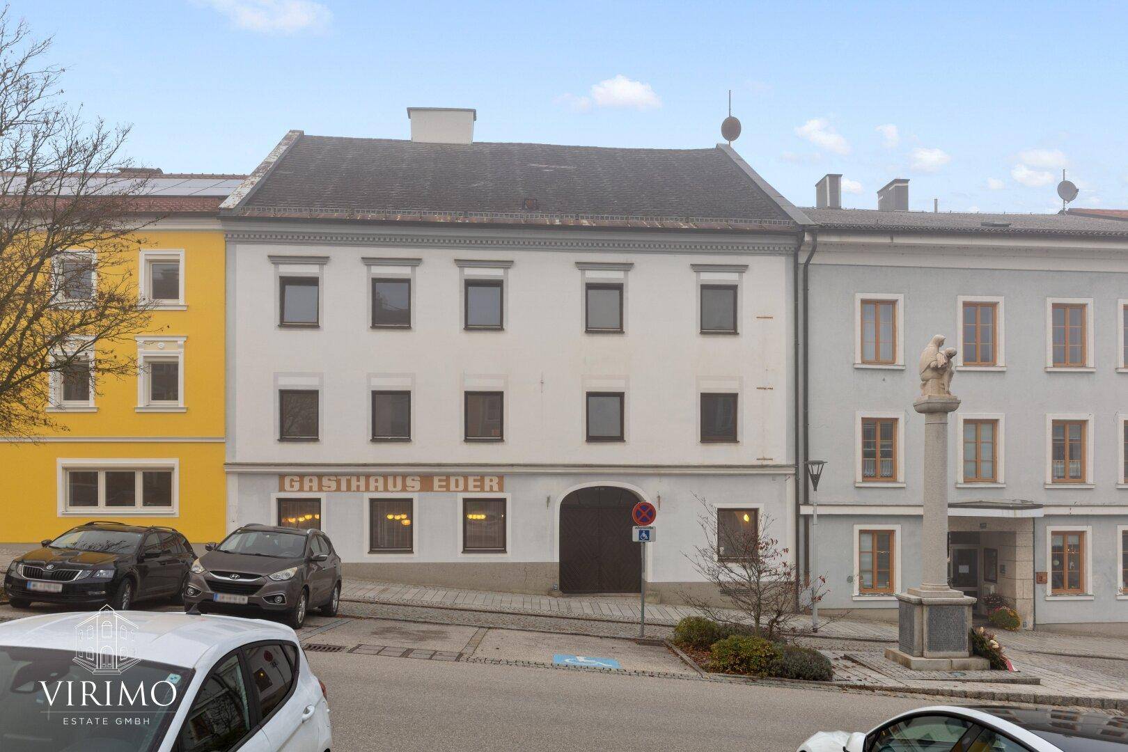 Historisches Gebäude mit traditioneller Architektur und Gasthaus-Beschriftung in einer Stadtansicht.