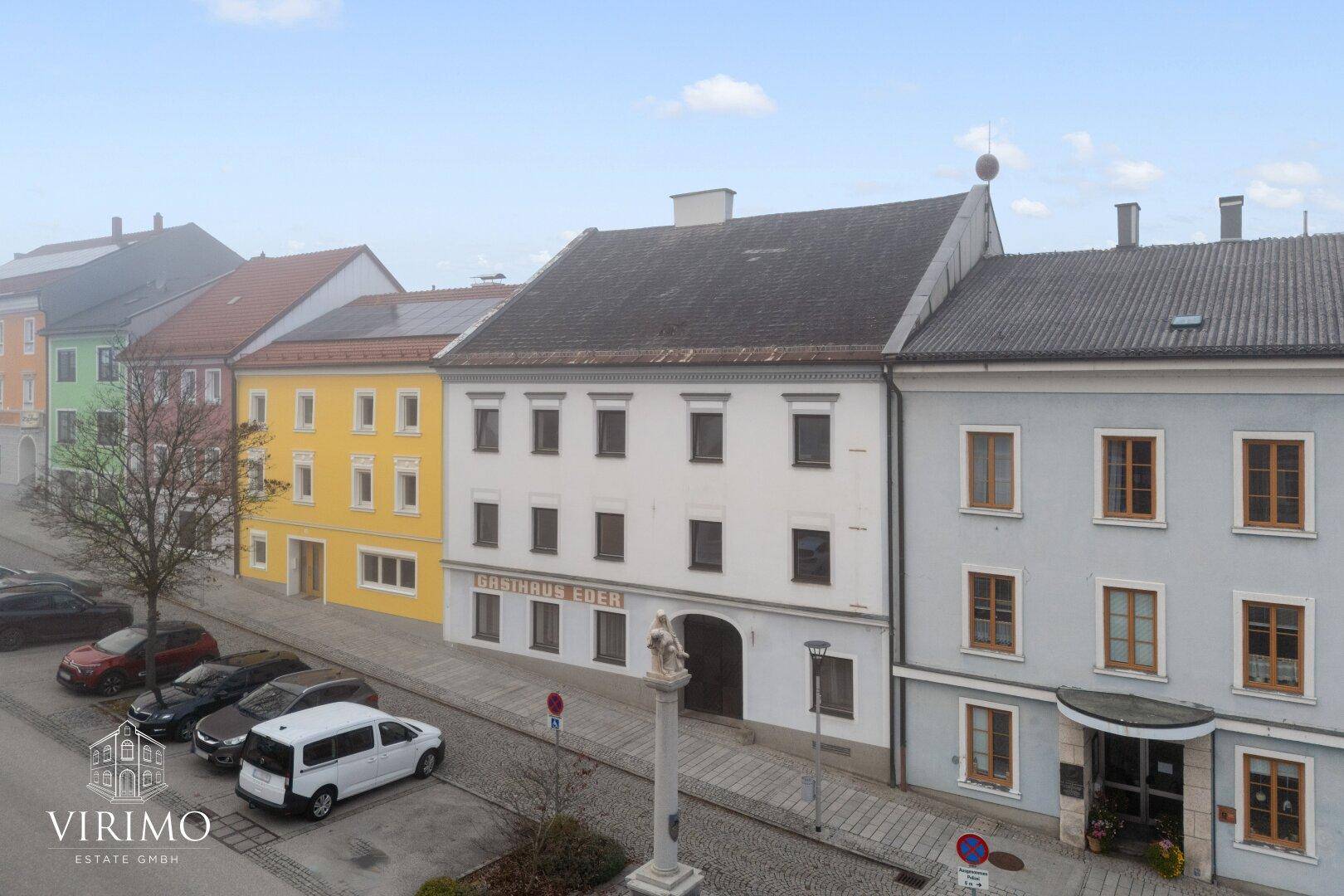 Historisches Gebäude mit traditioneller Architektur und Gasthaus-Beschriftung in einer Stadtansicht.