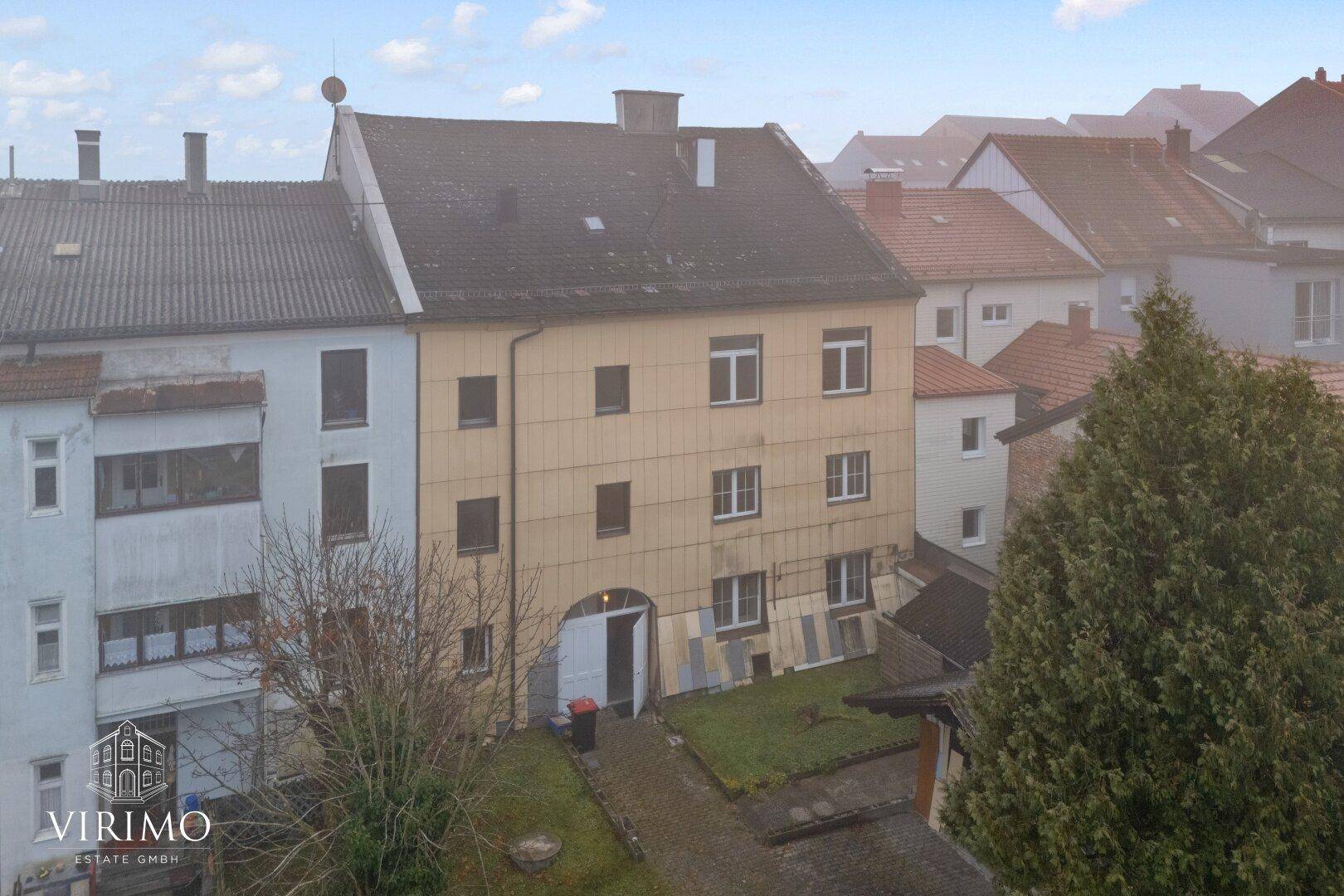 Rückseite des Gebäudes mit gelber Fassade, Fenstern und einem Hinterhof.
