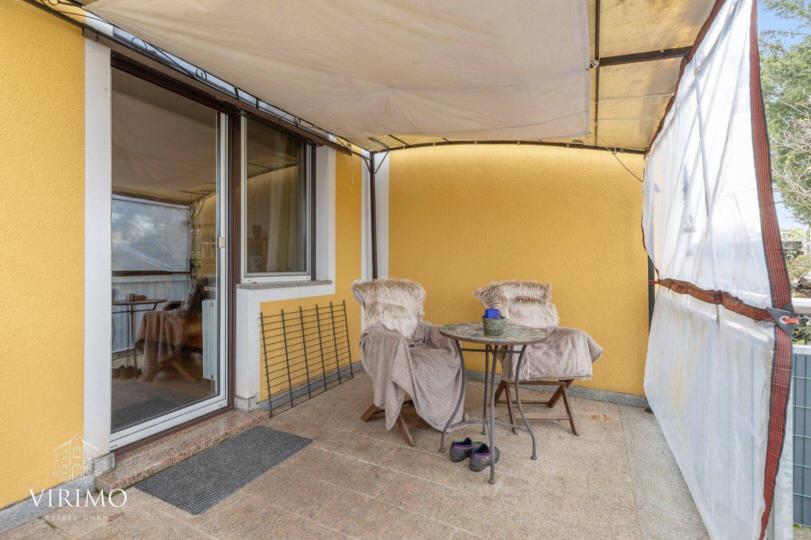 Überdachte Terrasse mit gemütlichen Sitzgelegenheiten und Blick ins Grüne.