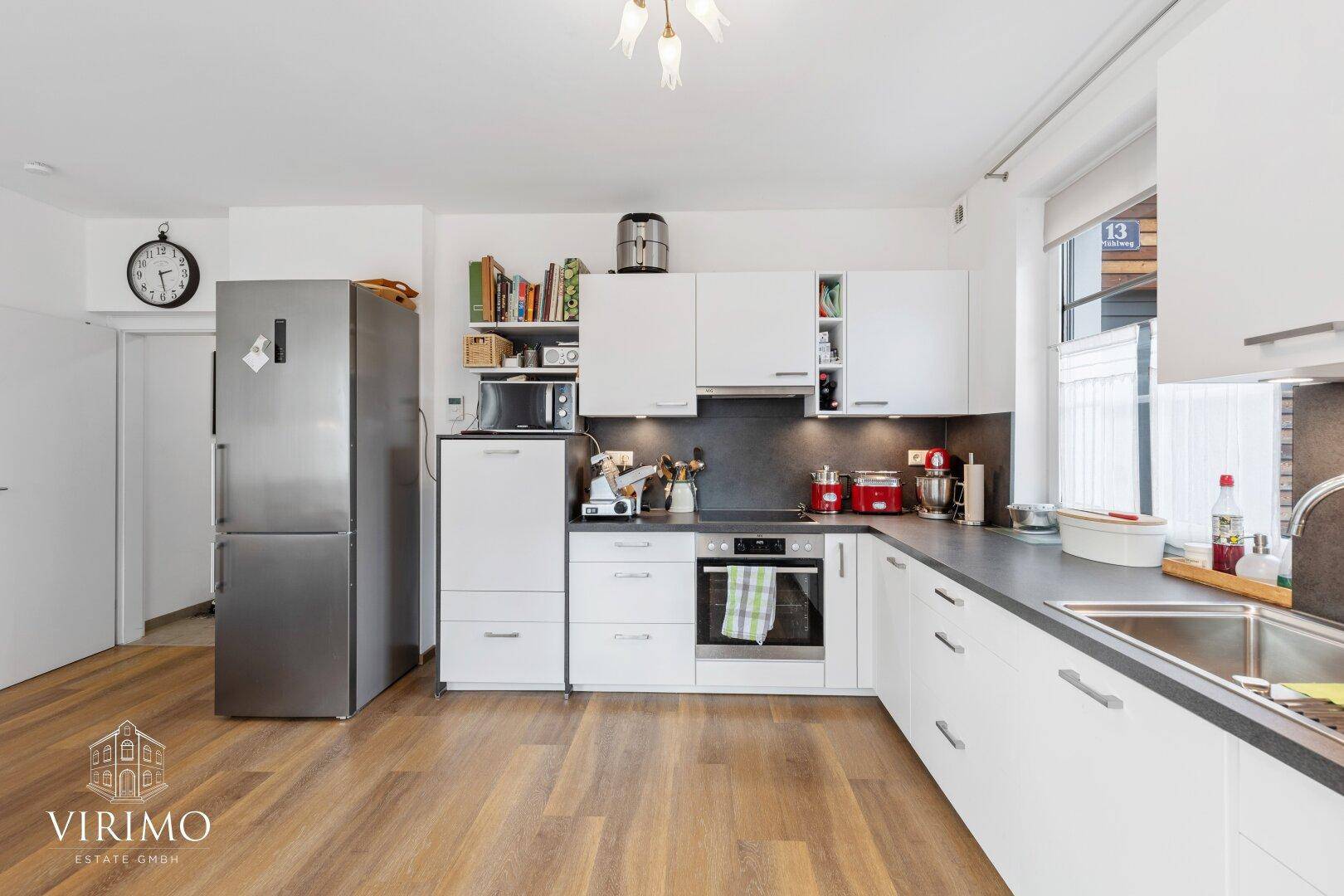 Funktionale Küche mit weißen Schränken, großem Kühlschrank und viel Arbeitsfläche.