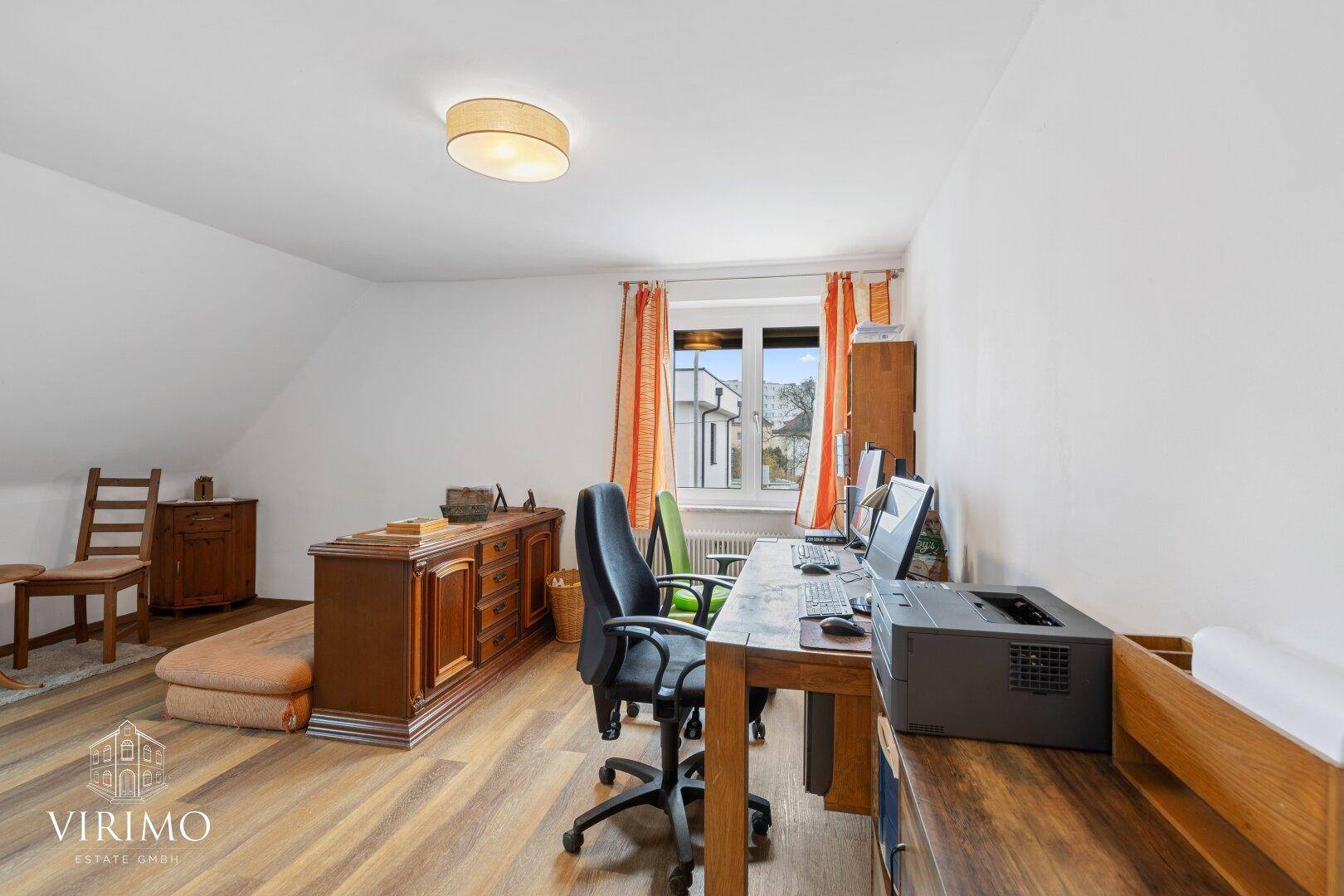 Geräumiges Arbeitszimmer im Dachgeschoss mit Holzboden, Dachschräge und Schreibtisch.