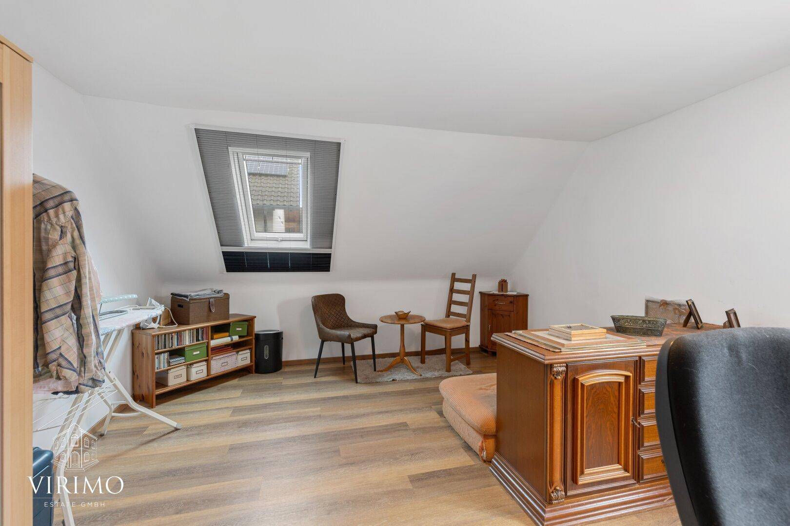 Helles Arbeitszimmer mit Dachfenster, Holzboden und zusätzlichen Sitzgelegenheiten.
