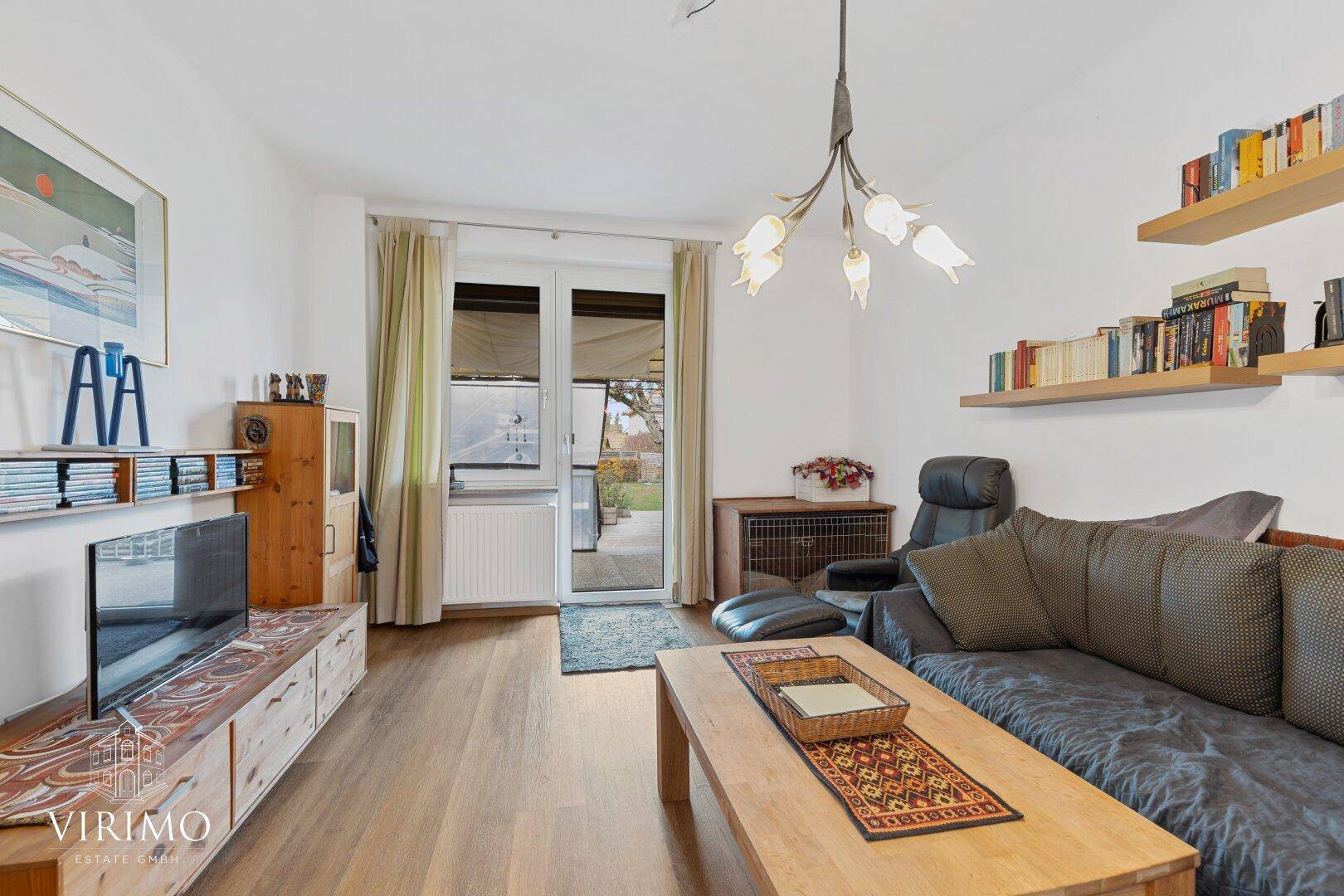 Gemütliches Wohnzimmer mit Laminatboden, Sofa und direktem Zugang zur Terrasse.