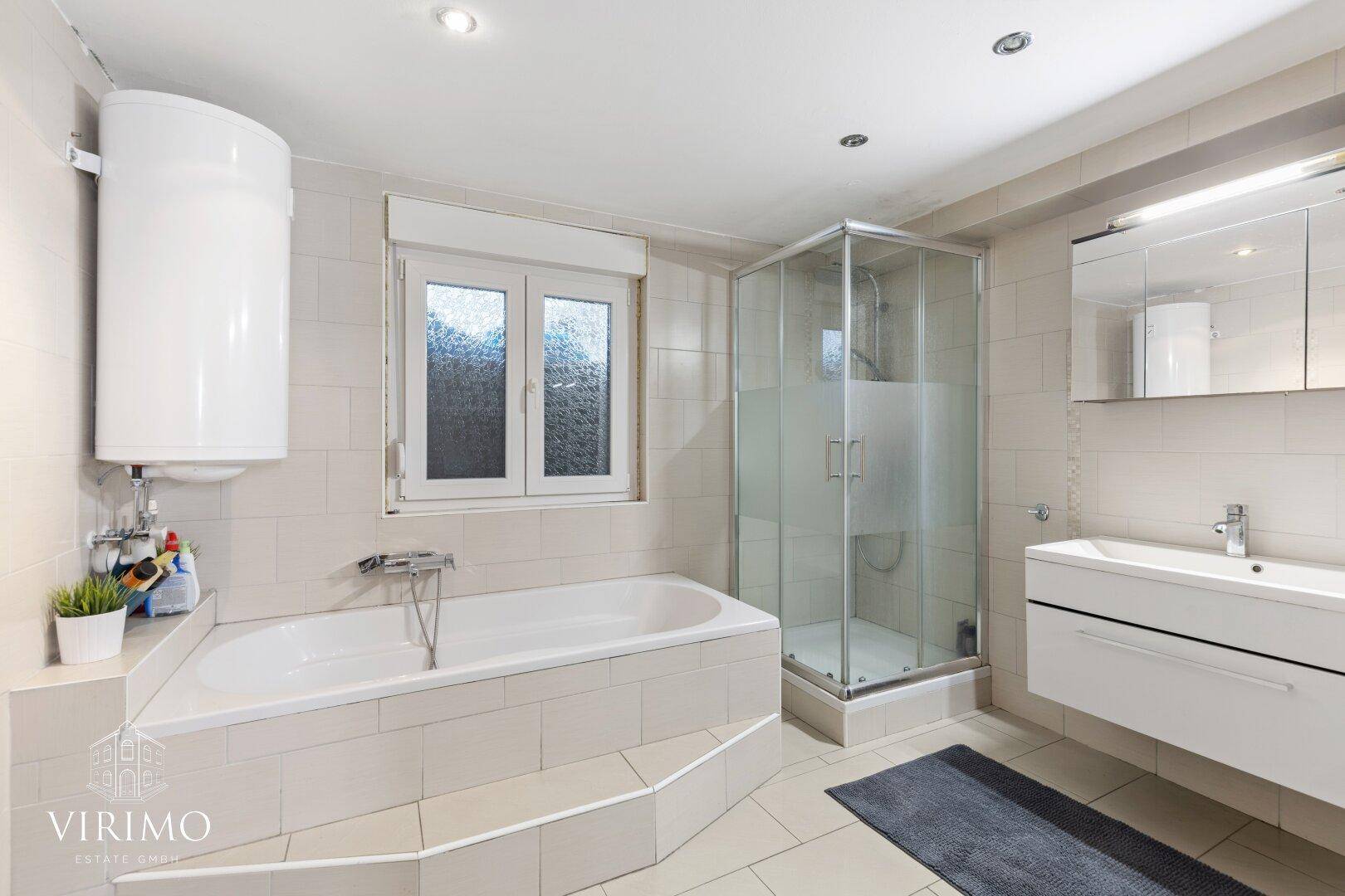 Geräumiges Badezimmer mit Eckbadewanne, Duschkabine und großem Waschtisch.