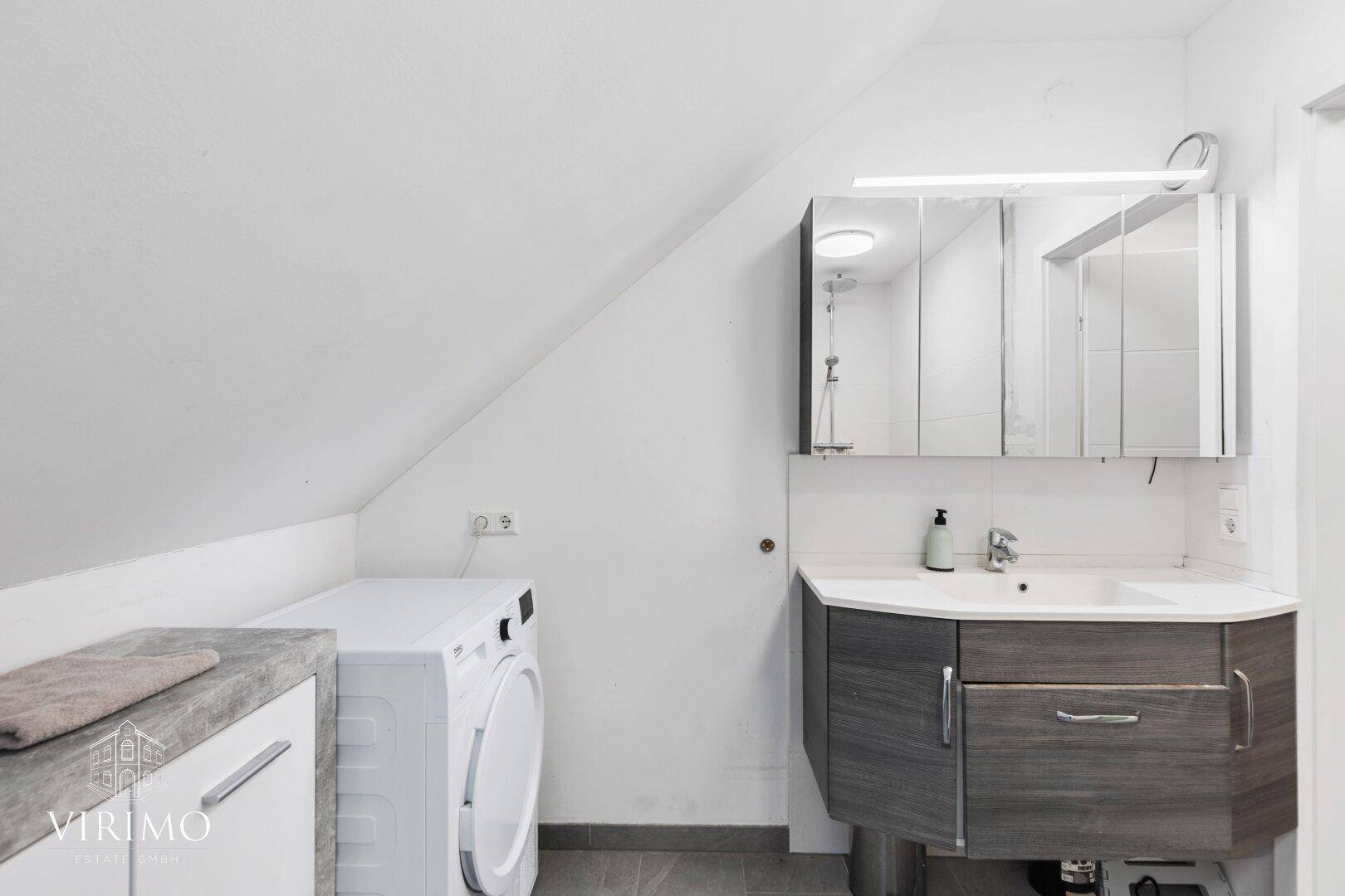 Modernes Badezimmer im Dachgeschoss mit Waschmaschine, Waschtisch und Spiegelschrank.