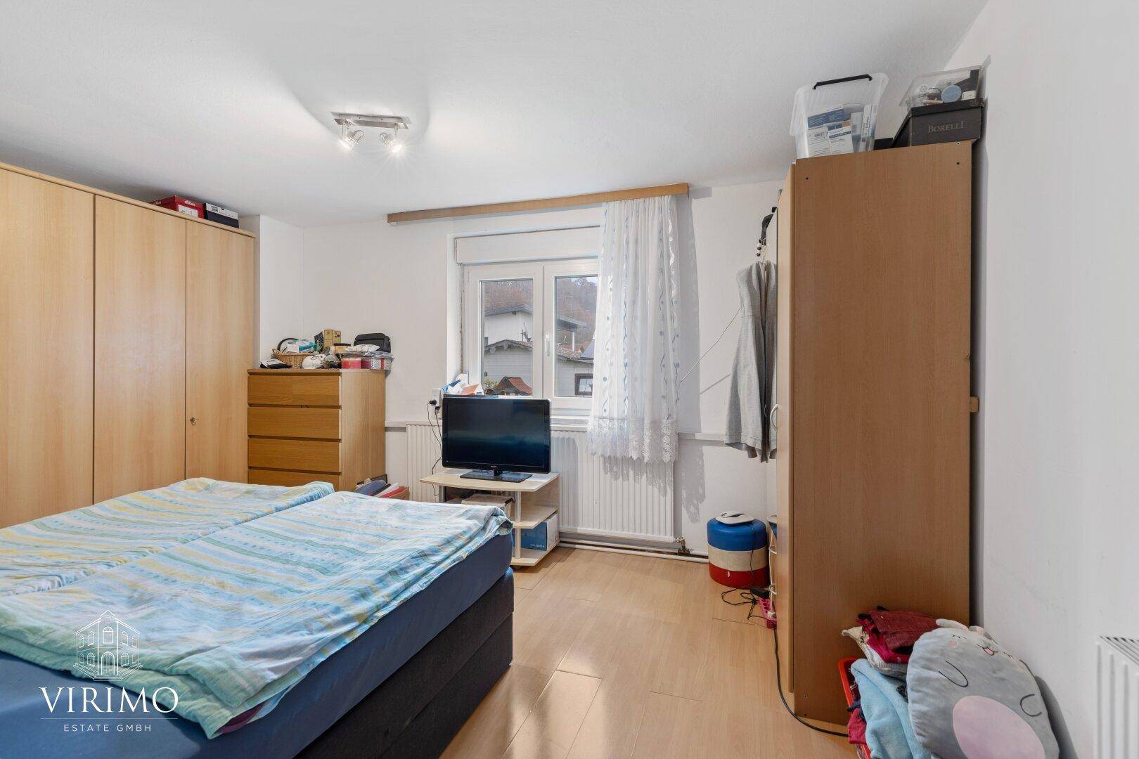 Schlafzimmer mit Doppelbett, Holzschränken und Fenster mit Blick auf die Umgebung.