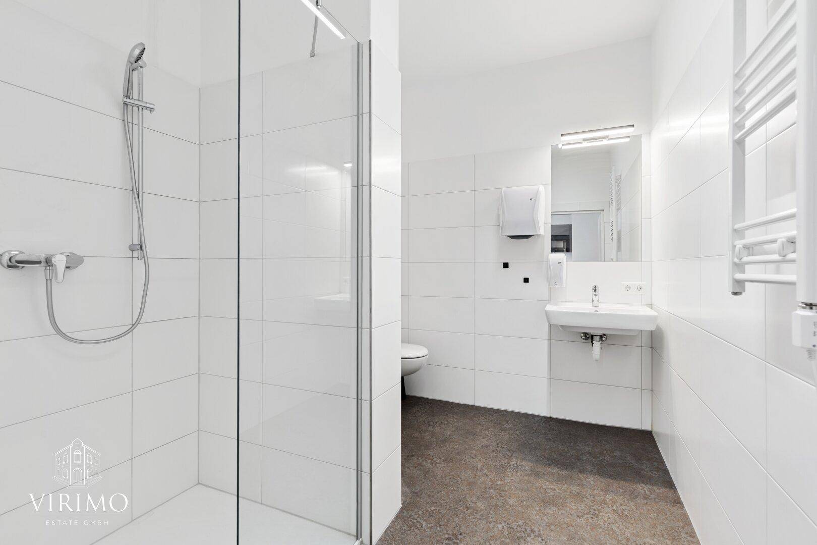 Helles Badezimmer mit großer Duschkabine, Waschbecken und weißer Wandverkleidung.