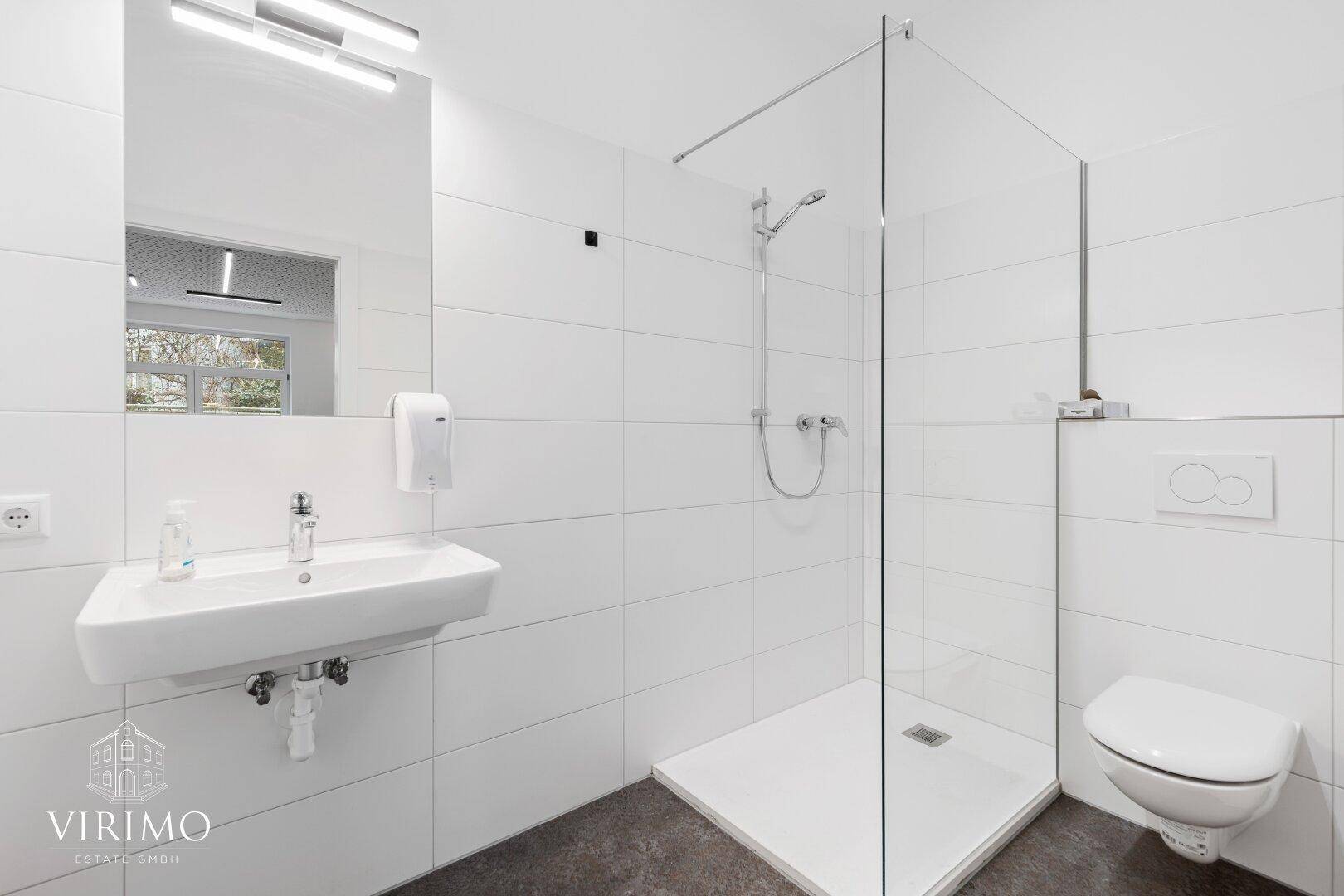 Modernes Badezimmer mit weiß gefliesten Wänden, ebenerdiger Dusche und wandhängendem WC.