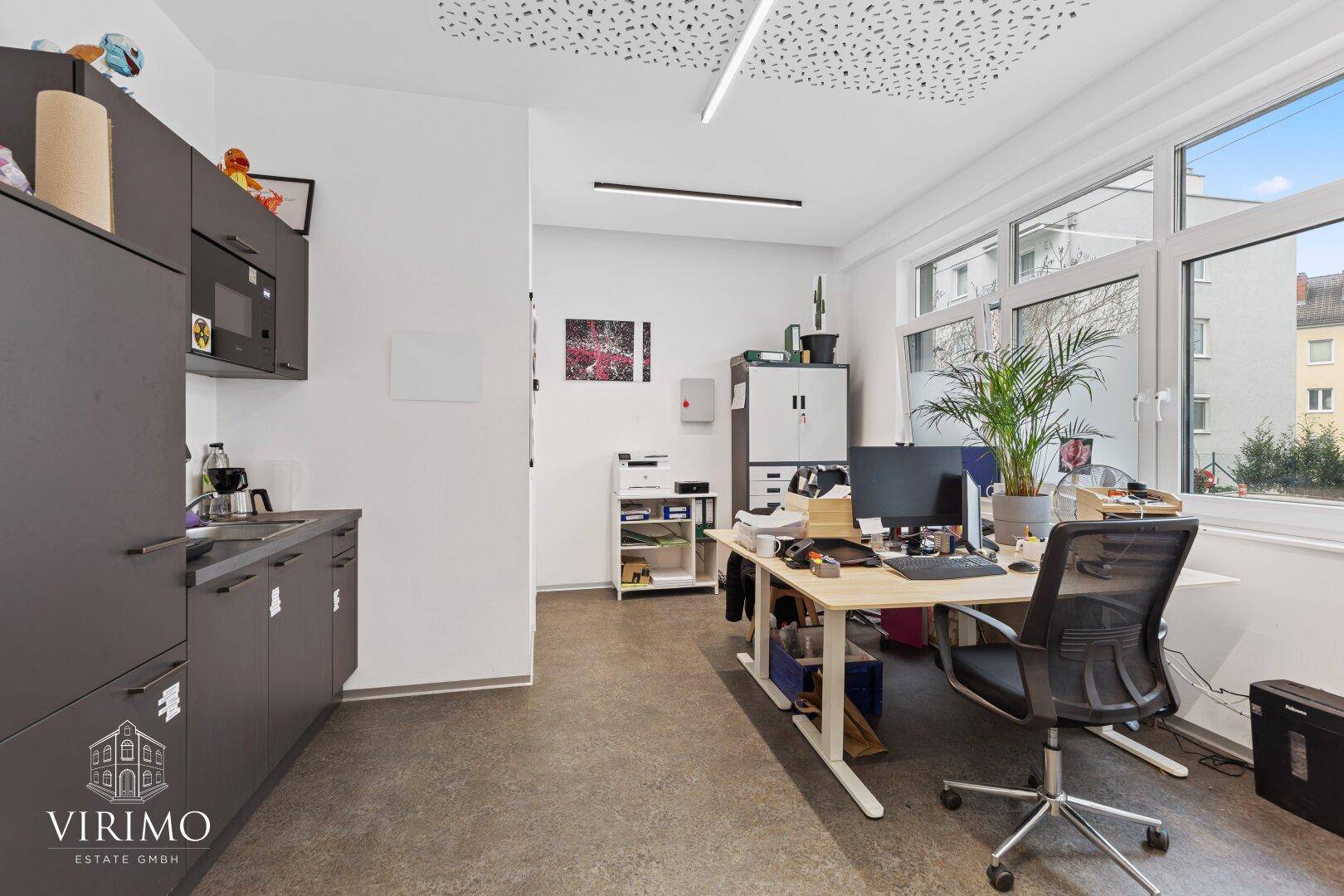Funktionaler Bürobereich mit Arbeitsplätzen, Stauraum und einer integrierten Küchenzeile.