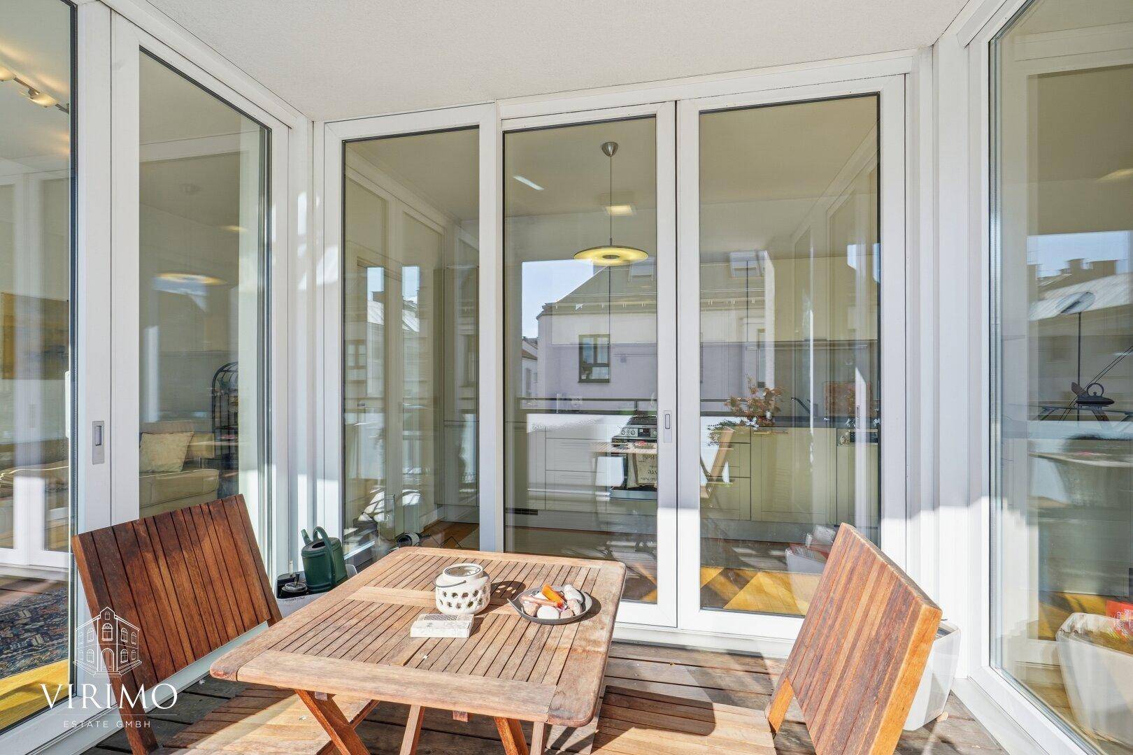 Heller Balkon mit Holzboden und Gartenmöbeln, bietet einen Blick in den Wohnbereich.
