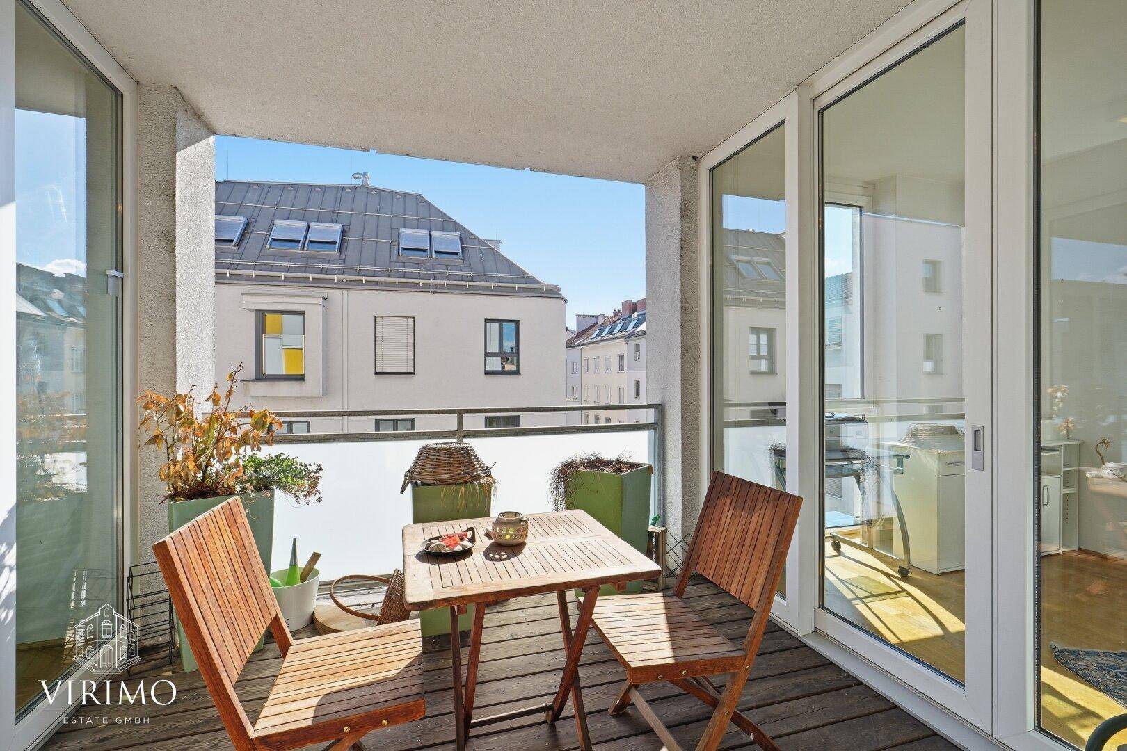 Balkon mit Holzboden und Sitzgelegenheiten, bietet einen weiten Blick über die Dächer der Stadt.